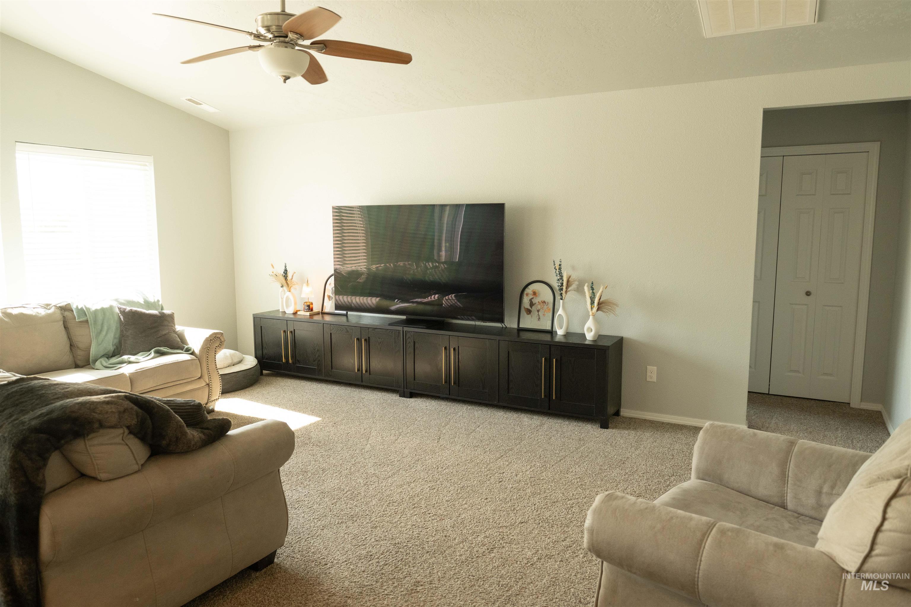 Living room featuring light colored carpet, lofted ceiling, and a ceiling fan