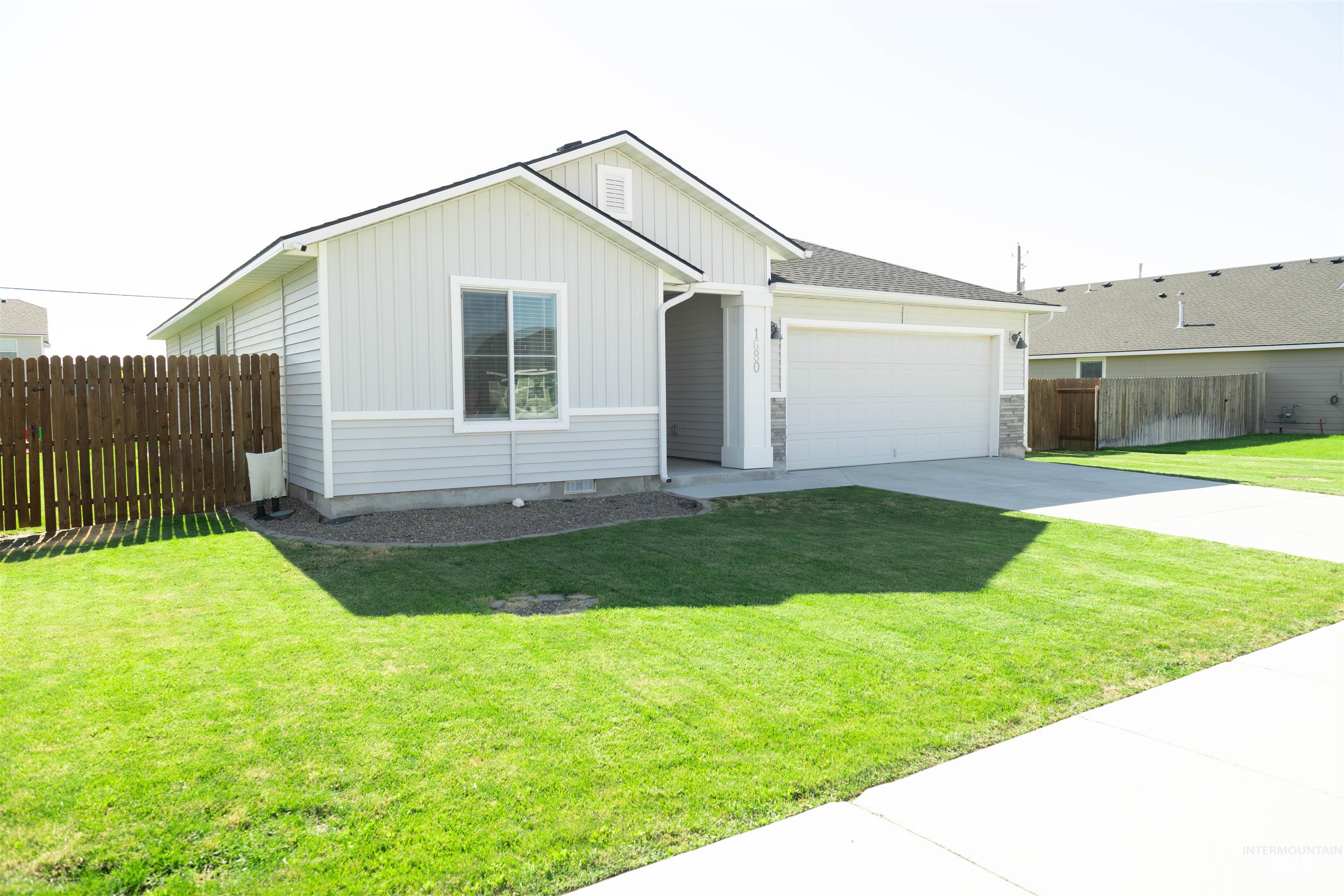 Single story home featuring board and batten siding, an attached garage, and driveway