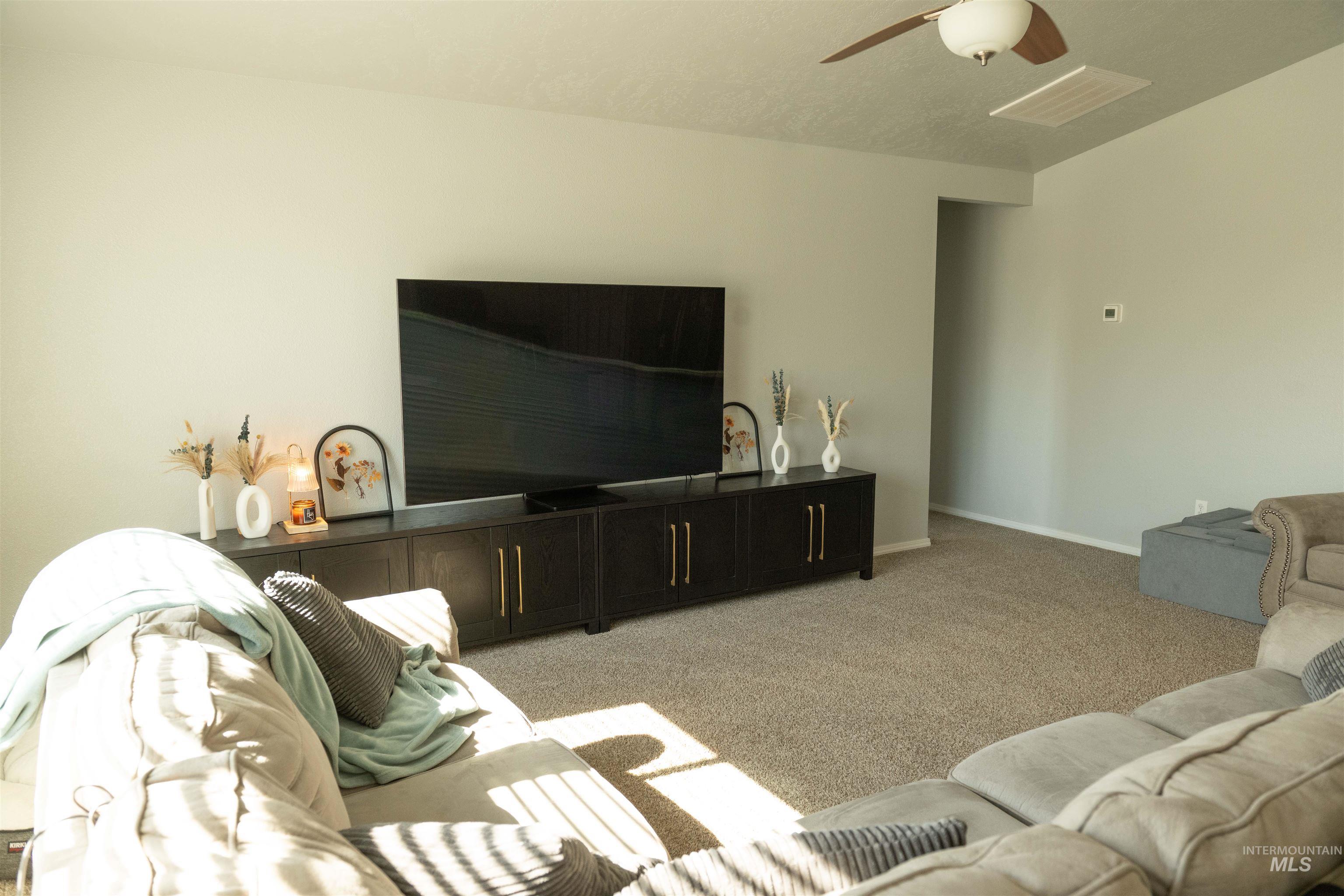 Living area with light colored carpet and ceiling fan