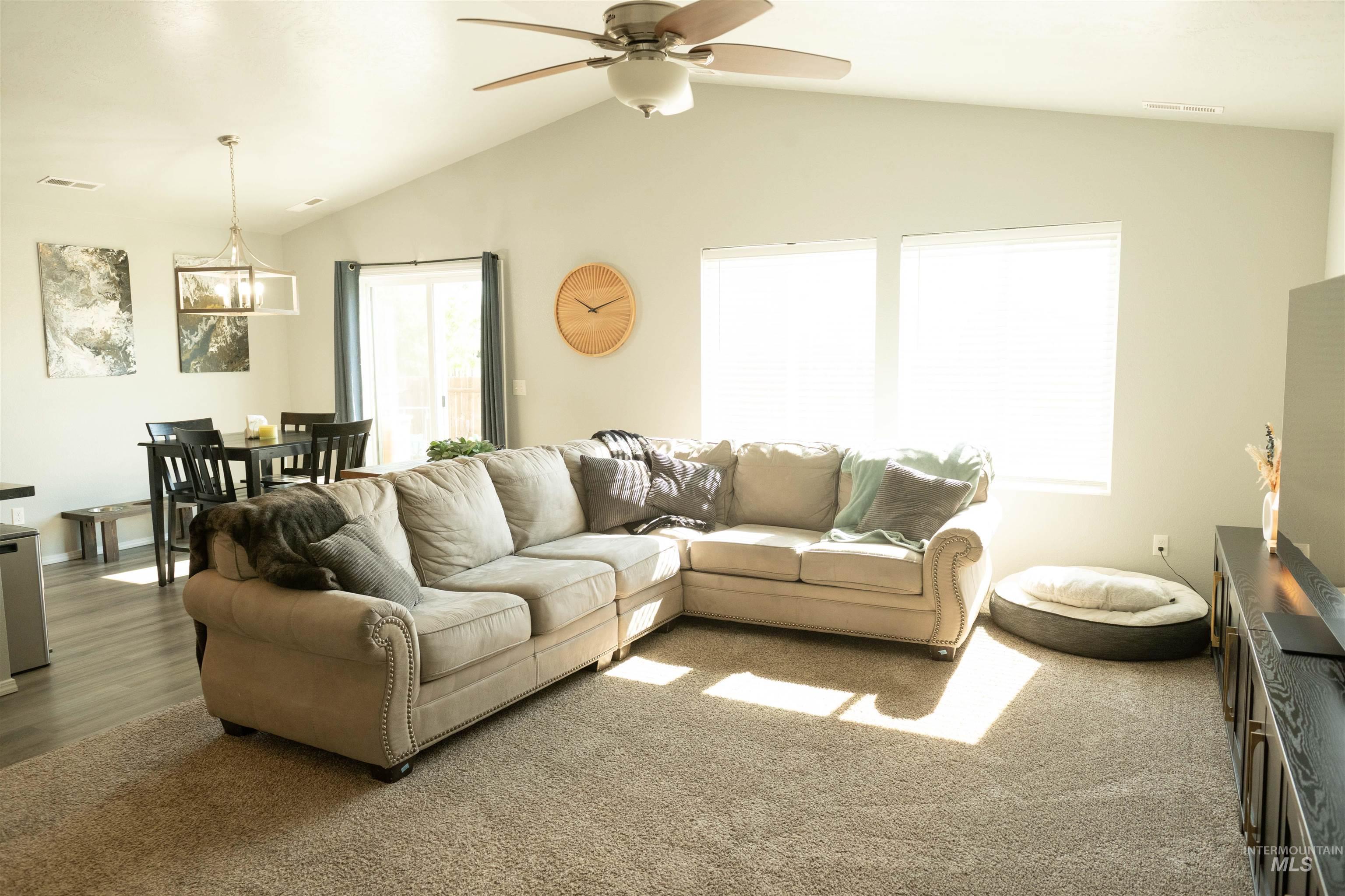 Living area with vaulted ceiling, a ceiling fan, and a chandelier