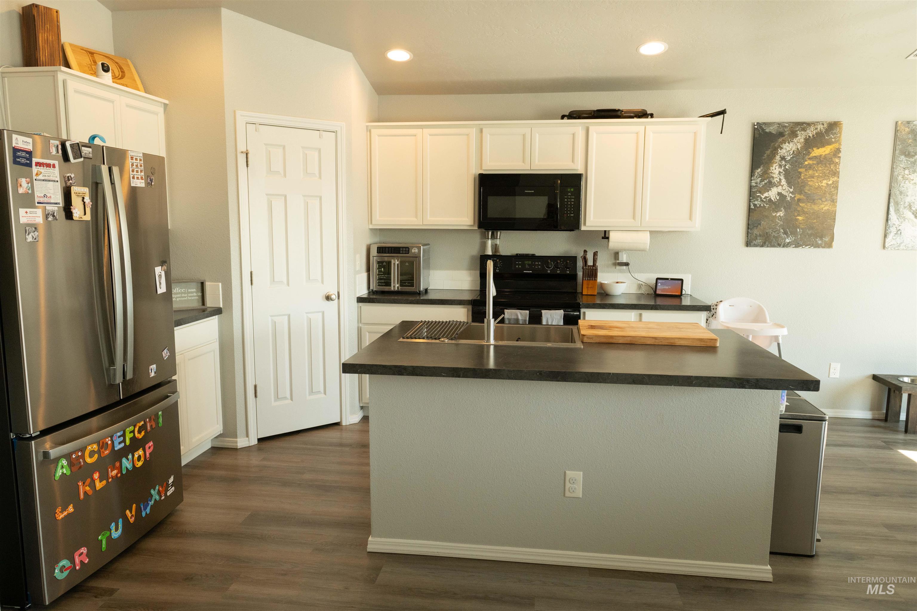 Kitchen featuring dark countertops, black appliances, white cabinets, recessed lighting, and dark wood-type flooring