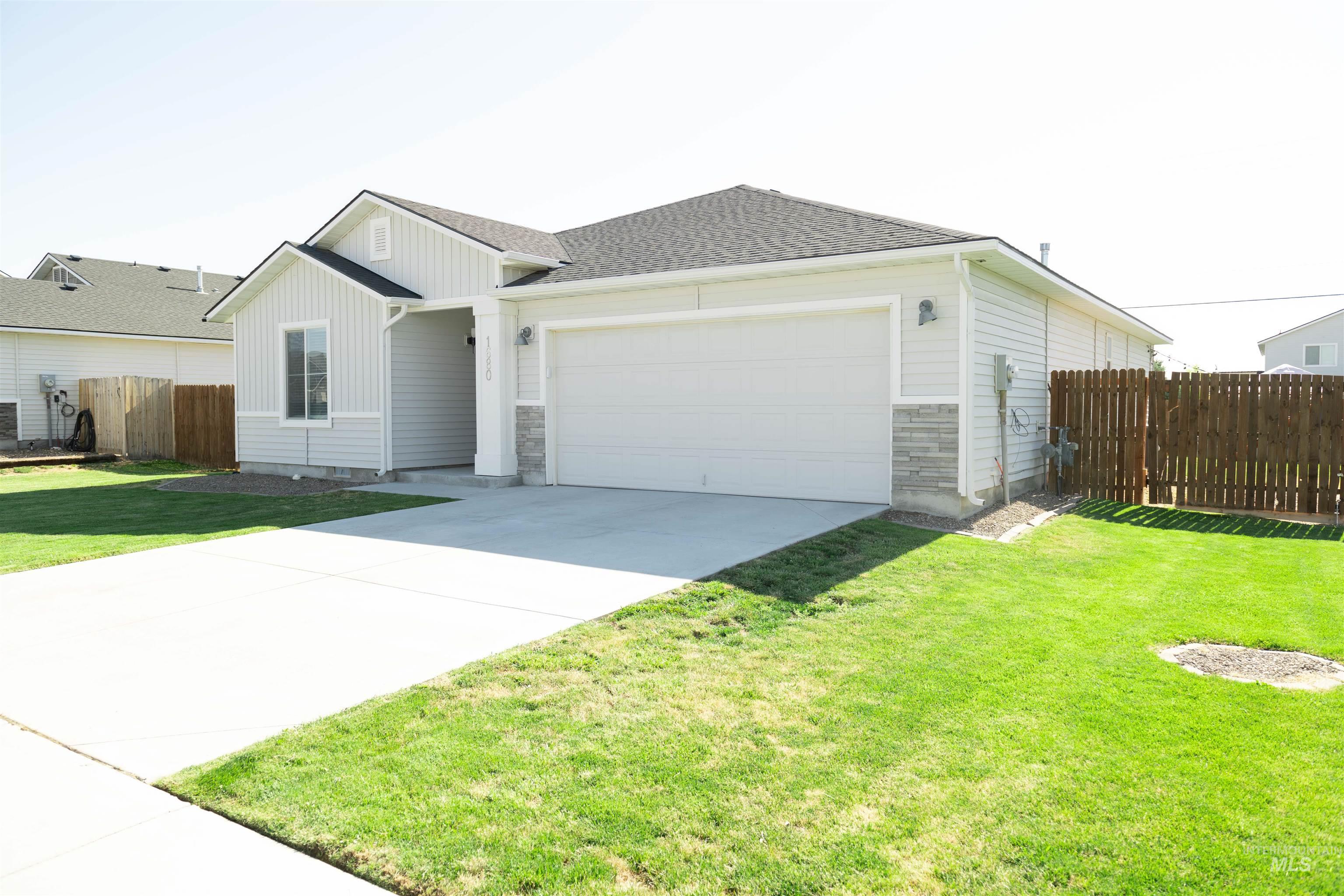View of front of home featuring board and batten siding, concrete driveway, a garage, stone siding, and roof with shingles