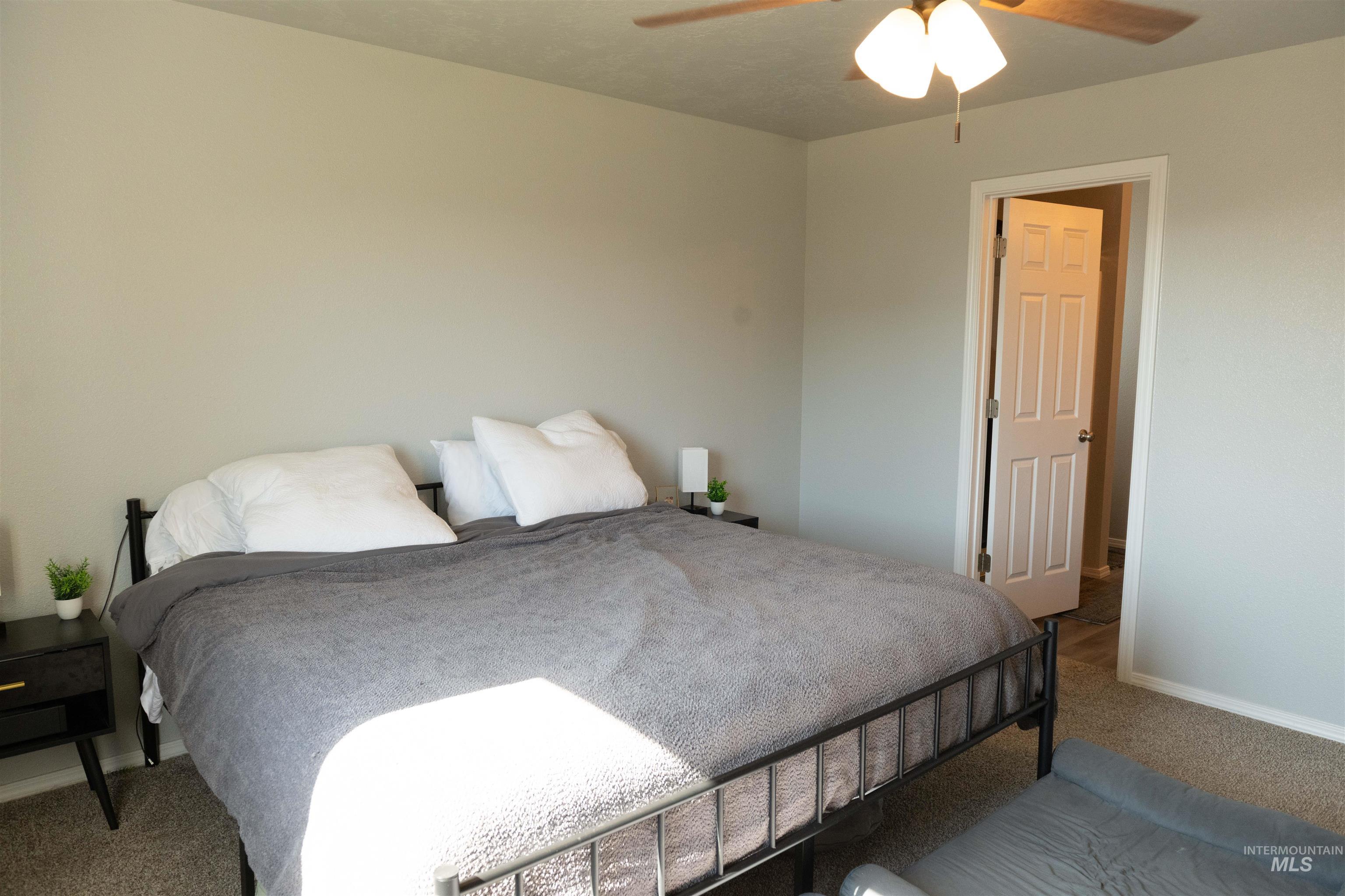 Carpeted bedroom featuring baseboards and ceiling fan