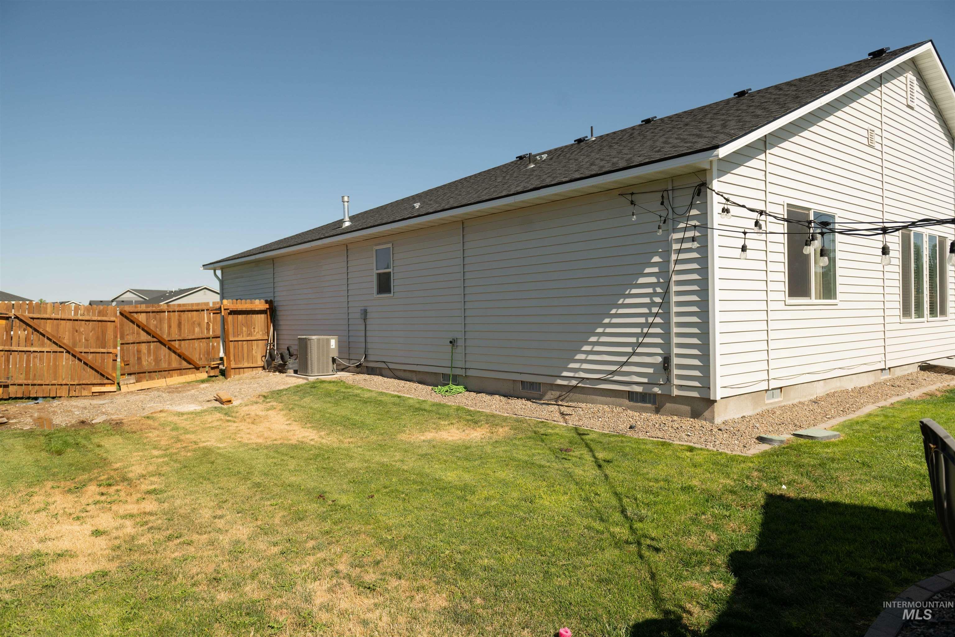 Back of property with roof with shingles and a gate