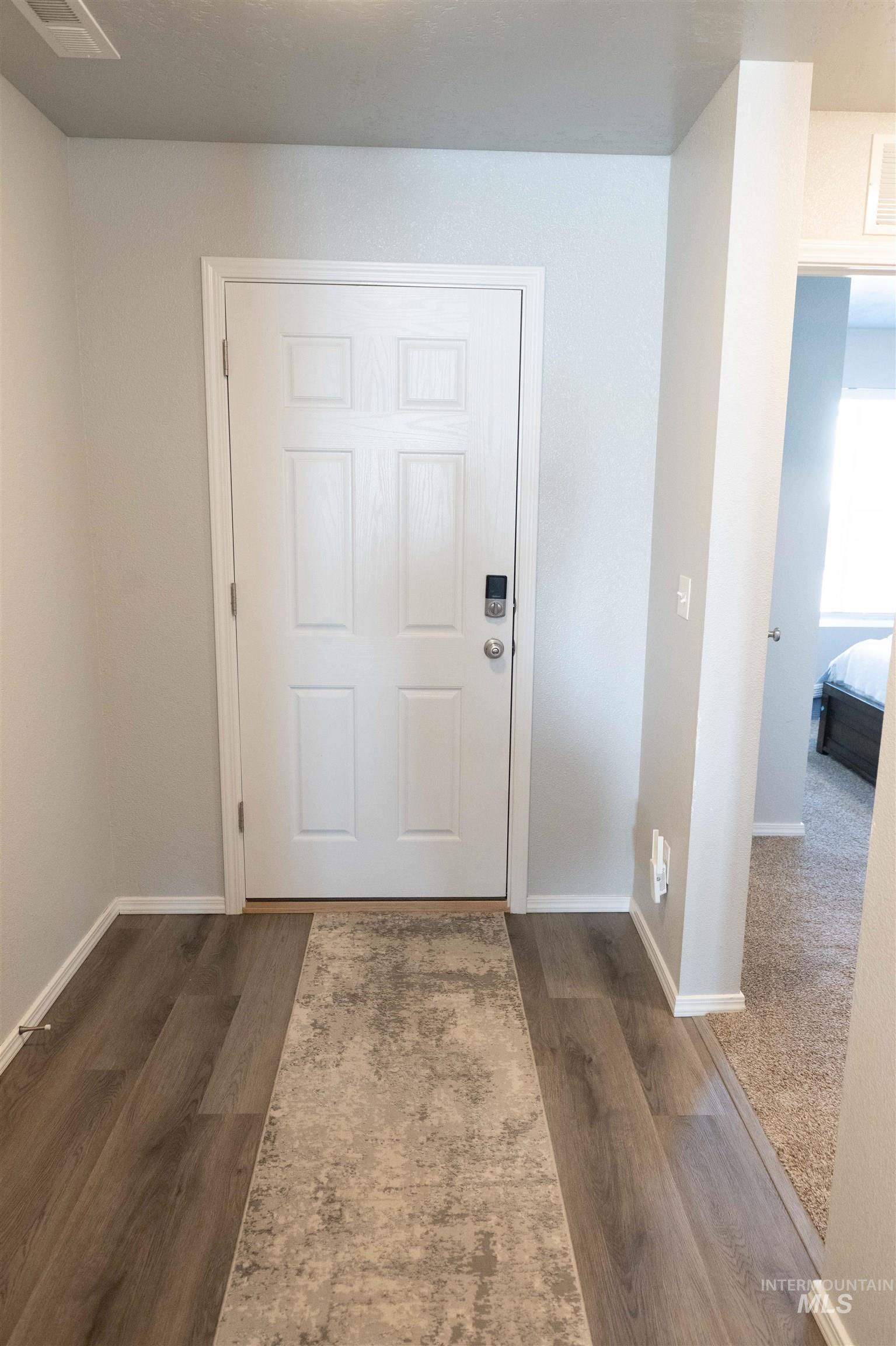 Doorway with baseboards and dark wood-style flooring