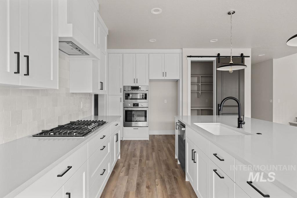 Kitchen with a barn door, white cabinetry, pendant lighting, and recessed lighting