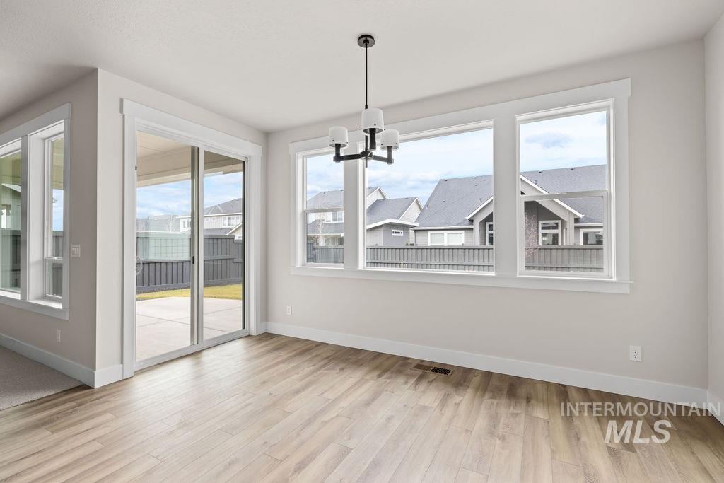 Unfurnished dining area with light wood-style floors, healthy amount of natural light, and a chandelier