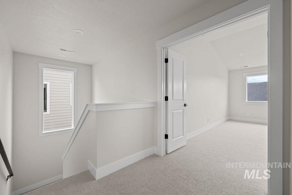 Hall with an upstairs landing, light carpet, and a textured ceiling