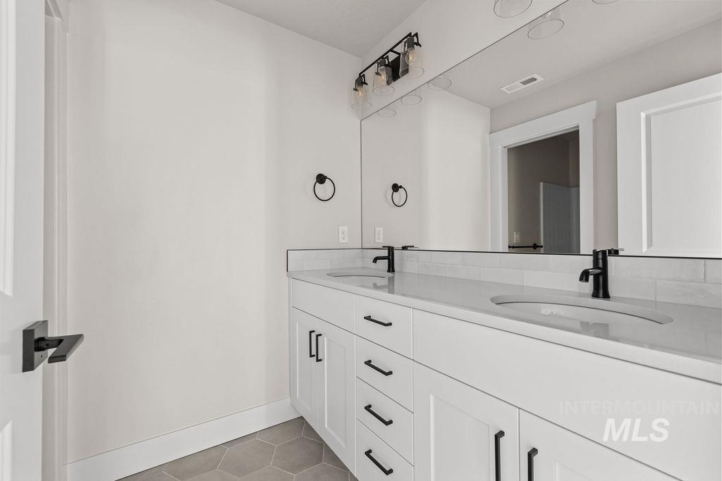 Bathroom with double vanity and light tile patterned floors