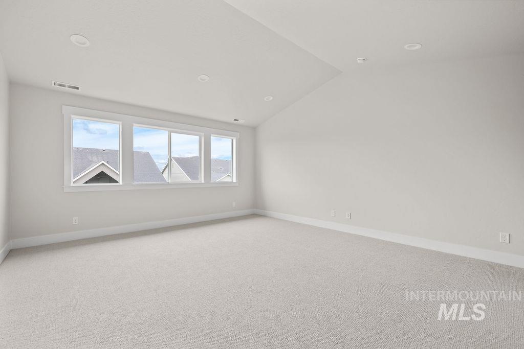 Carpeted empty room with lofted ceiling and baseboards