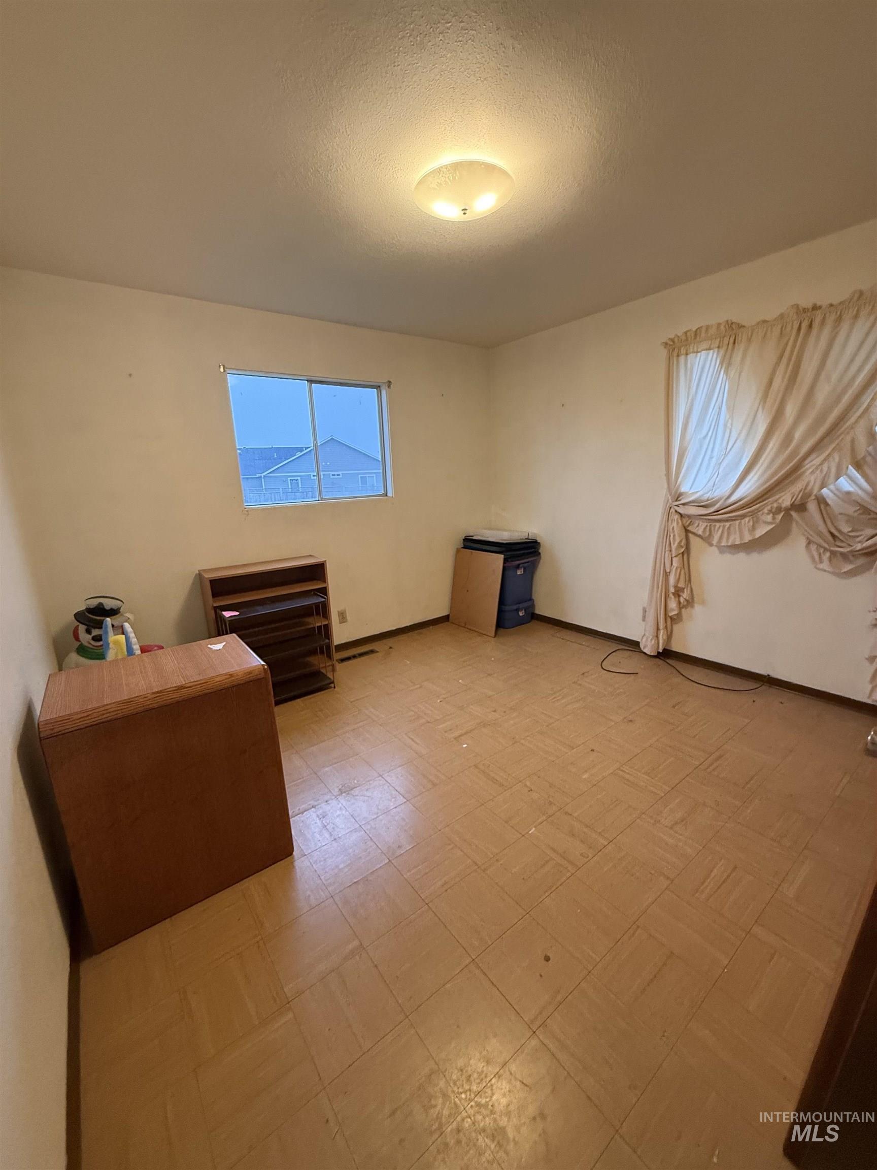Unfurnished bedroom featuring light floors and a textured ceiling