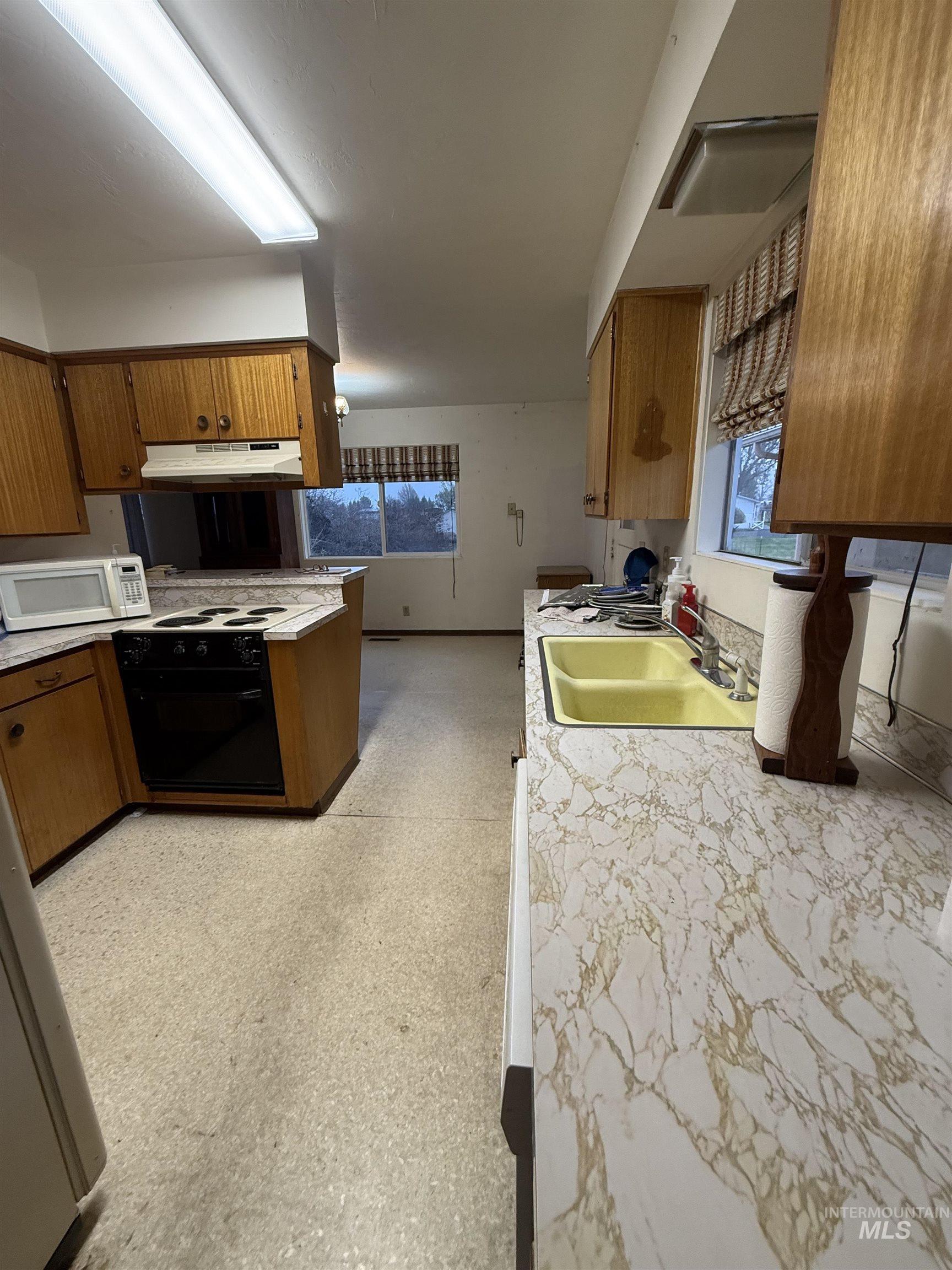 Kitchen with light flooring, light countertops, white microwave, and healthy amount of natural light