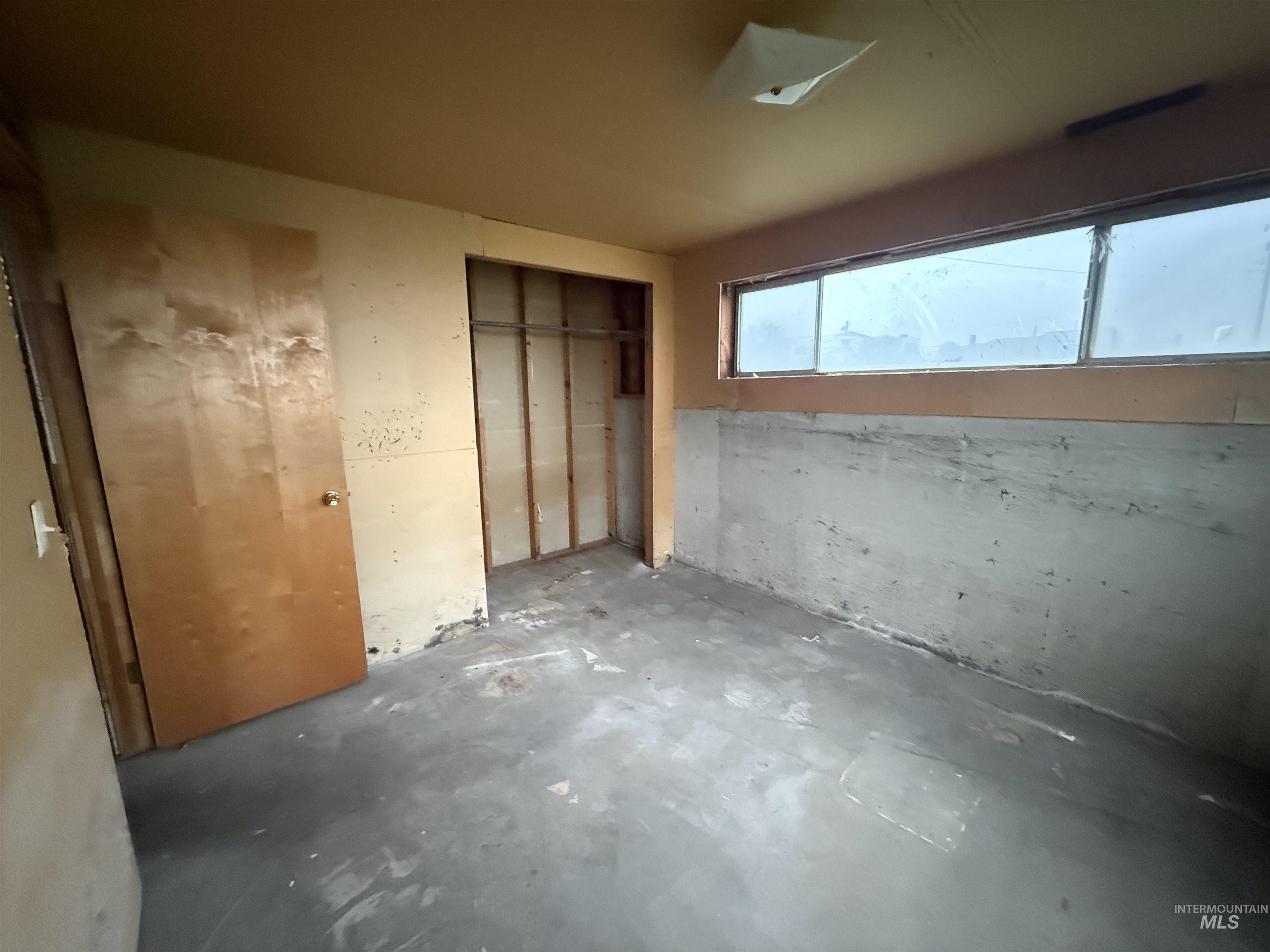 Unfurnished bedroom featuring concrete flooring and a closet