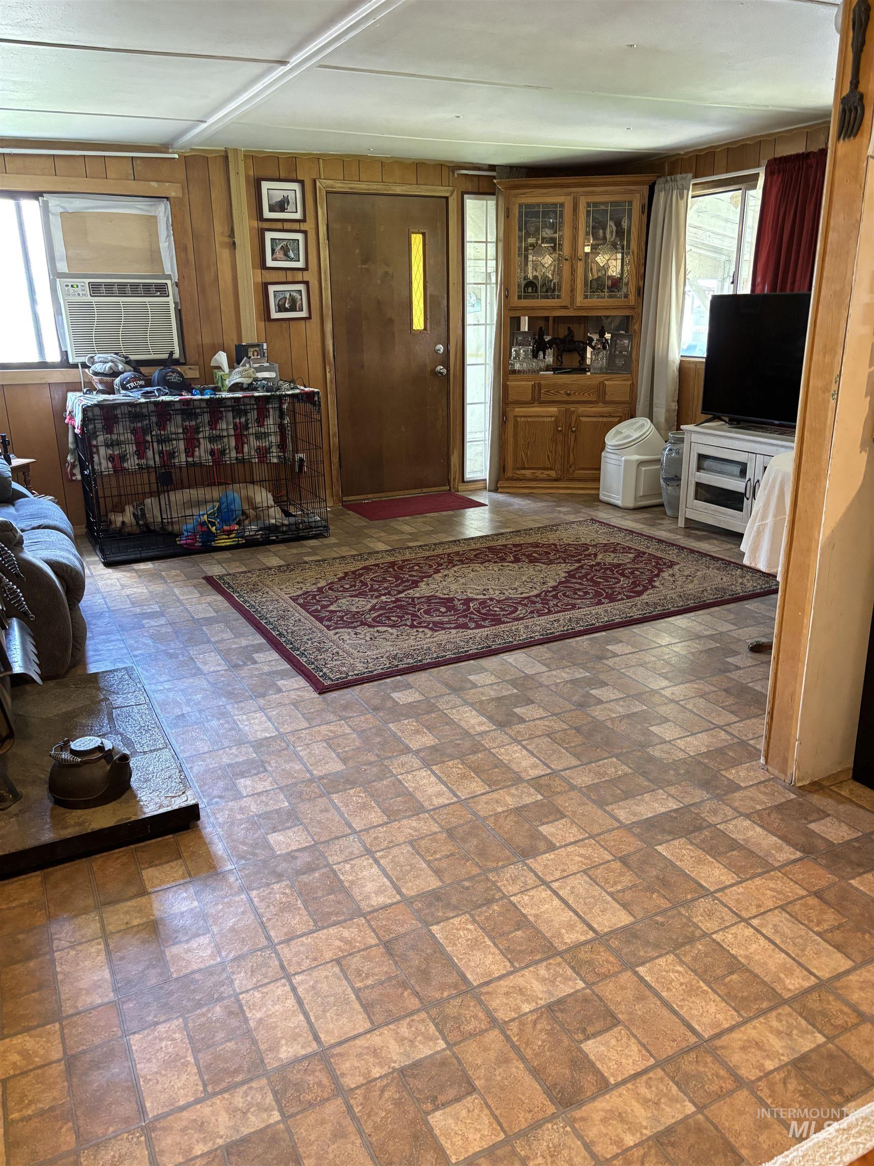Living room featuring brick patterned floors, cooling unit, and wooden walls