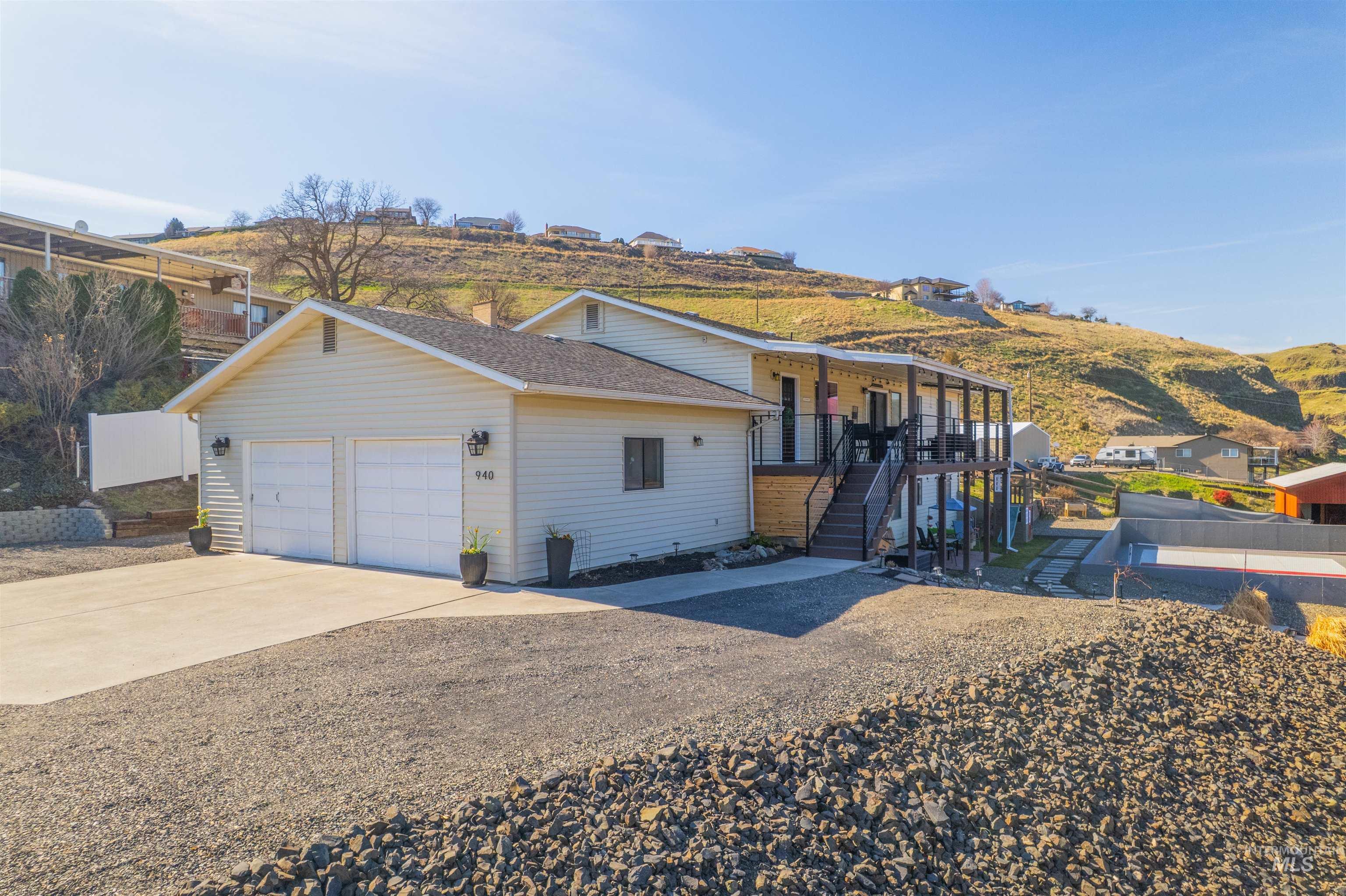 View of front facade featuring driveway, a garage, and a shingled roof