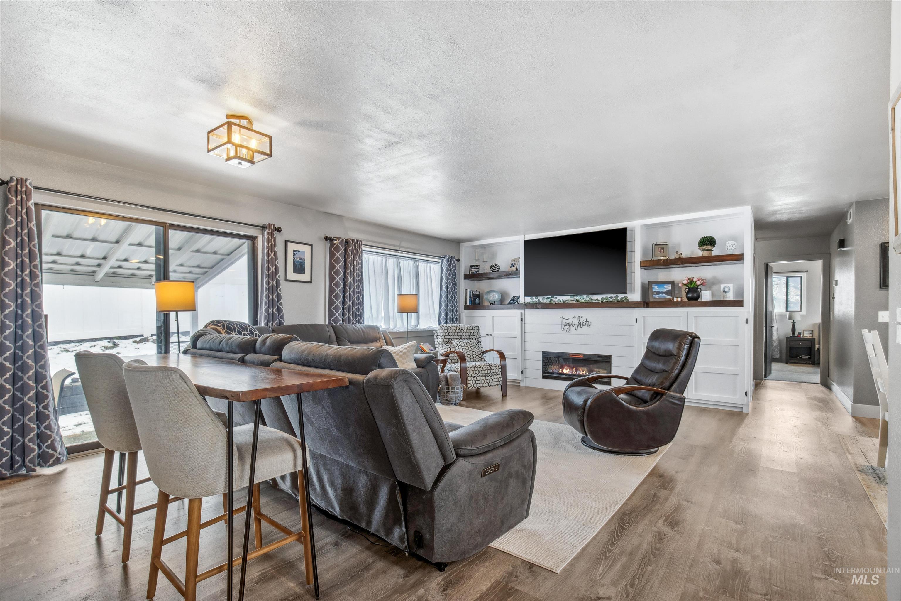 Living room with light wood-style flooring and a glass covered fireplace