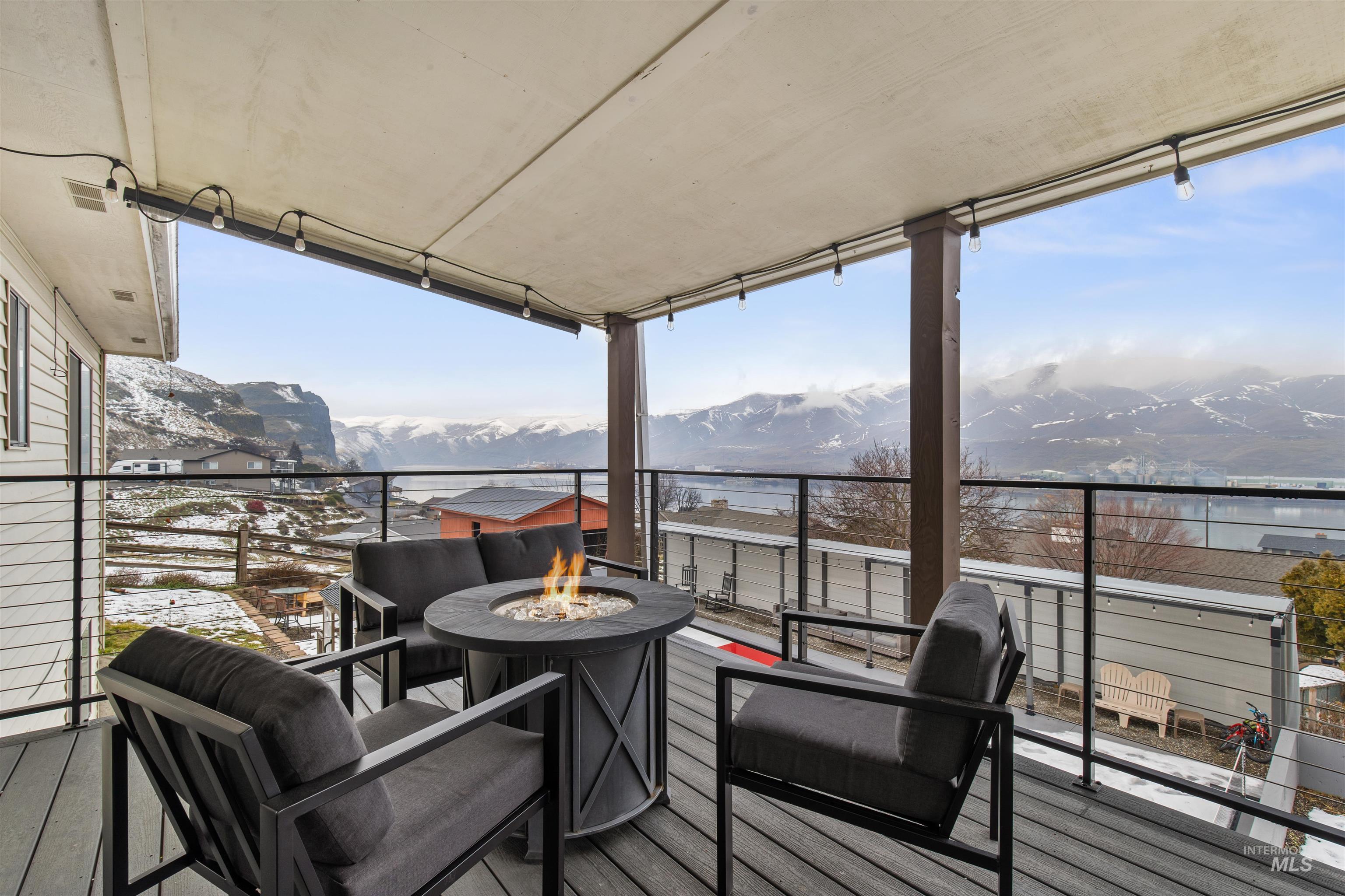 Wooden deck featuring an outdoor fire pit and a water and mountain view