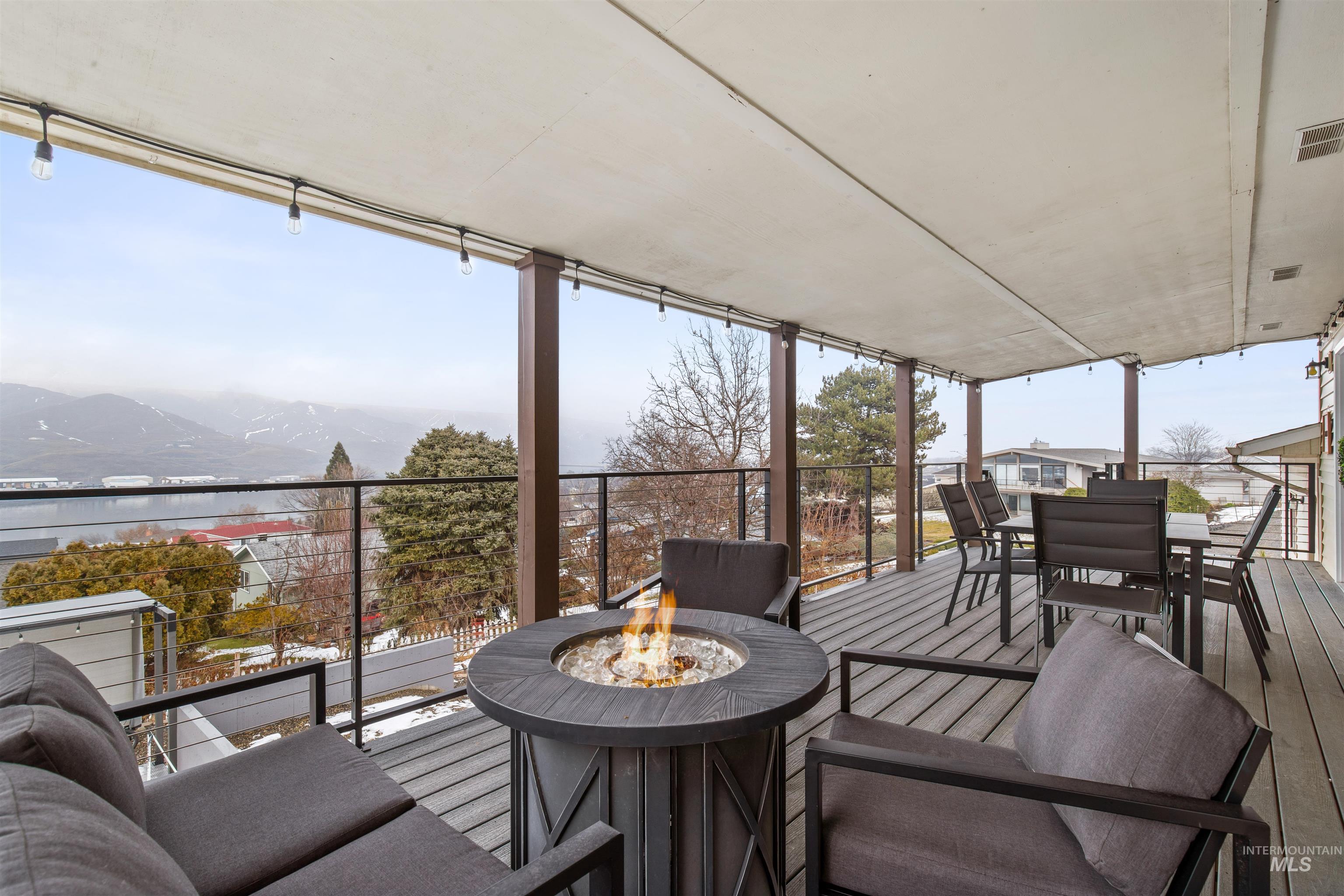 Wooden deck featuring a fire pit, outdoor dining space, and a water view