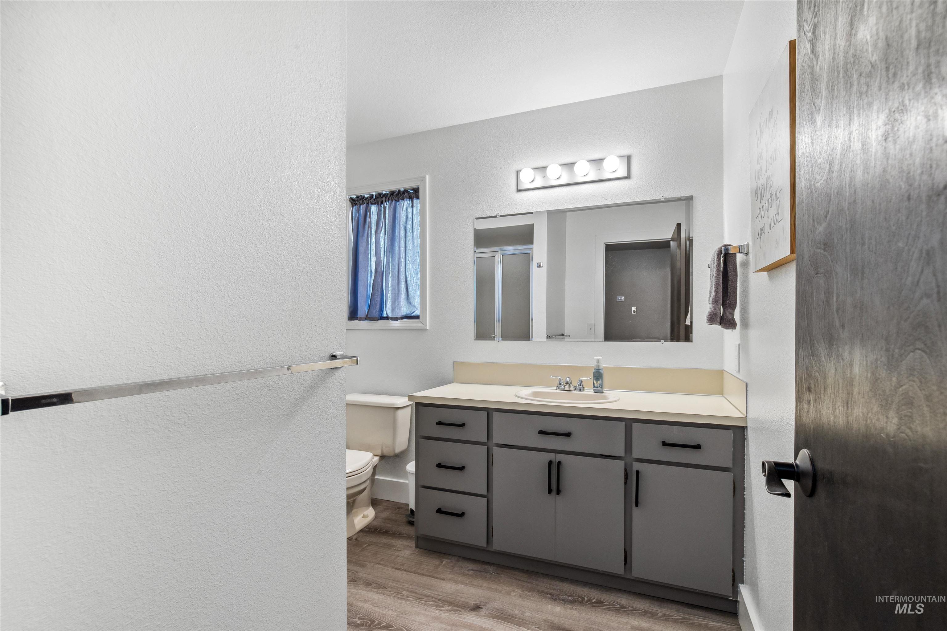 Bathroom featuring a stall shower, vanity, light wood-style flooring, and a textured wall