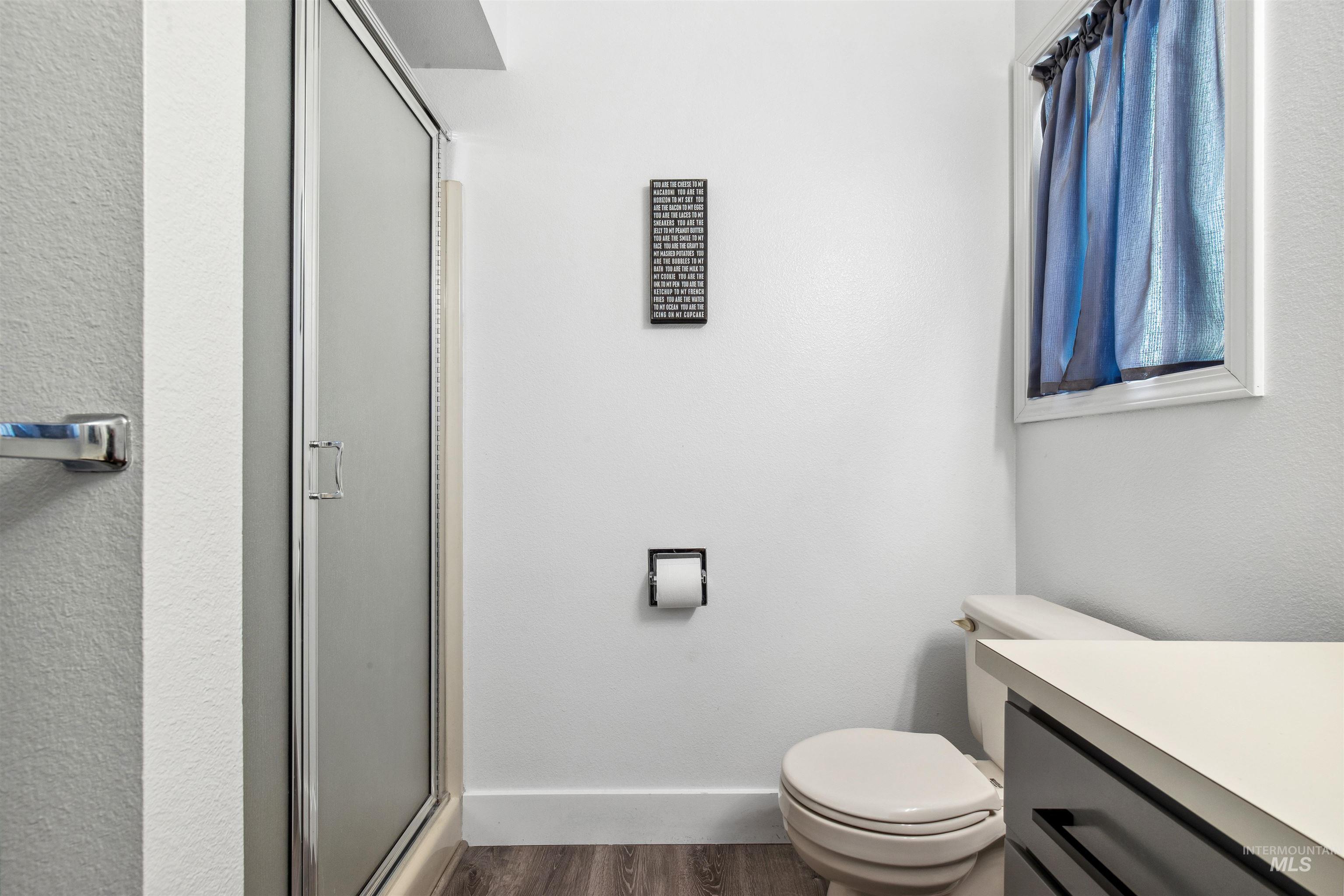 Full bath with vanity, a stall shower, dark wood-type flooring, and a textured wall