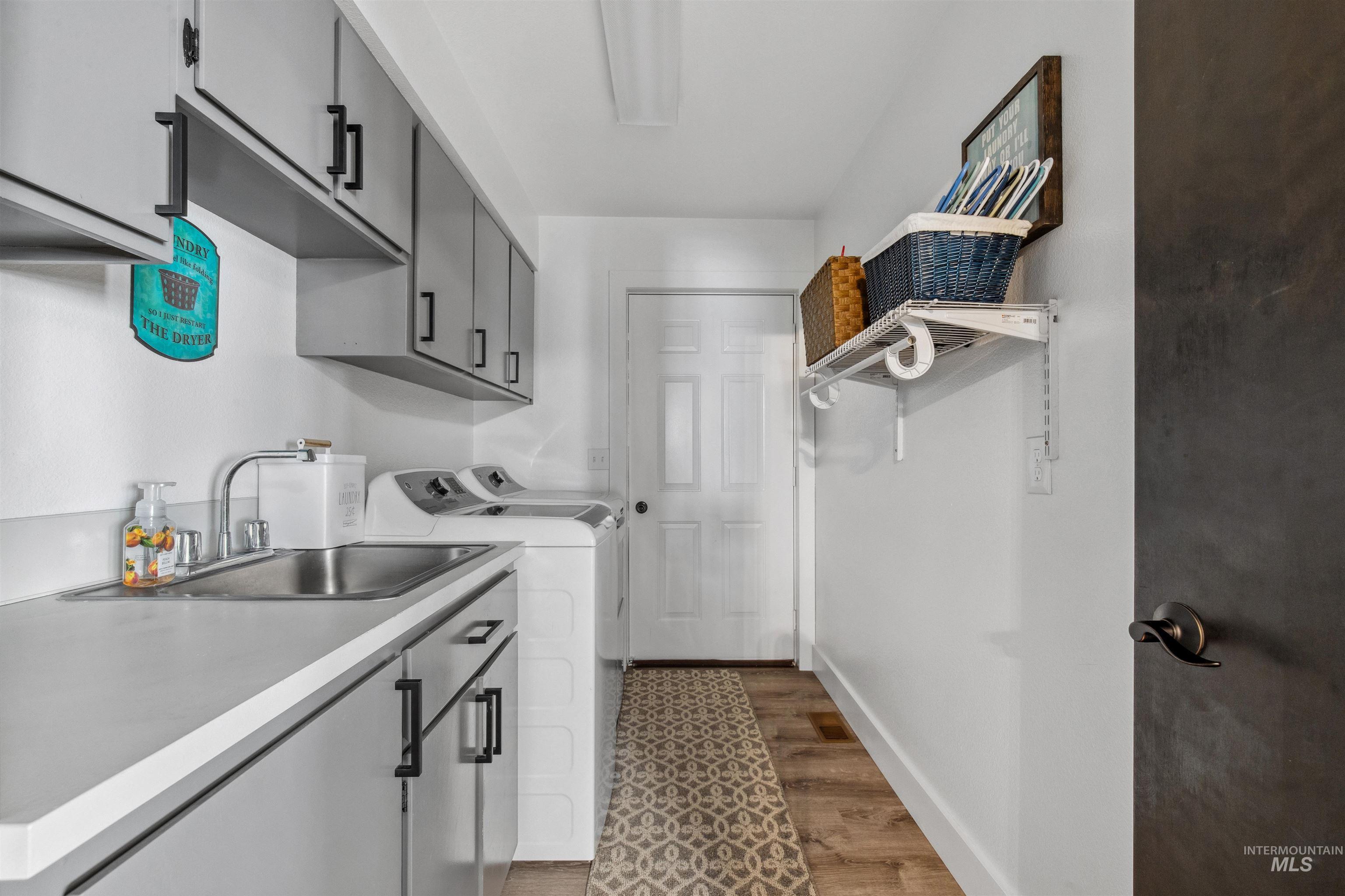 Washroom with cabinet space, light wood-style floors, and separate washer and dryer