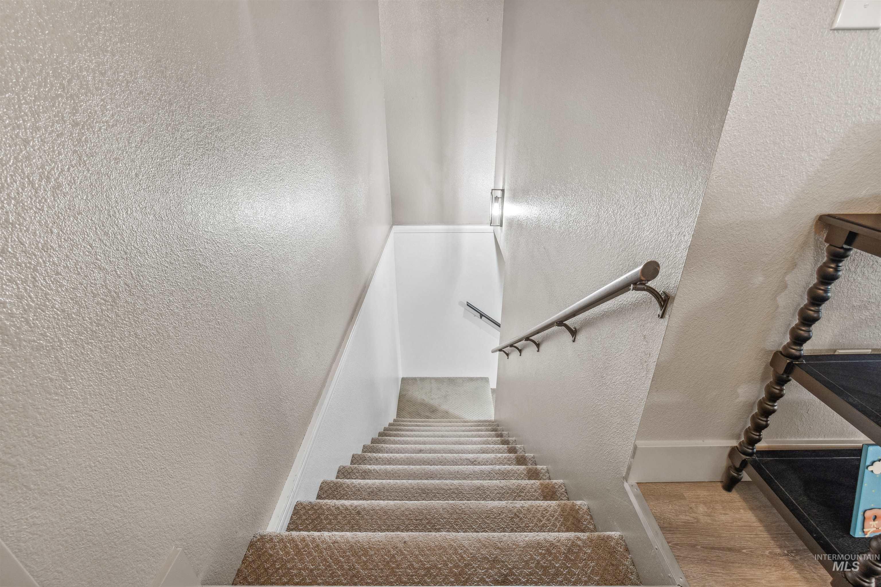 Stairway with a textured wall and wood finished floors