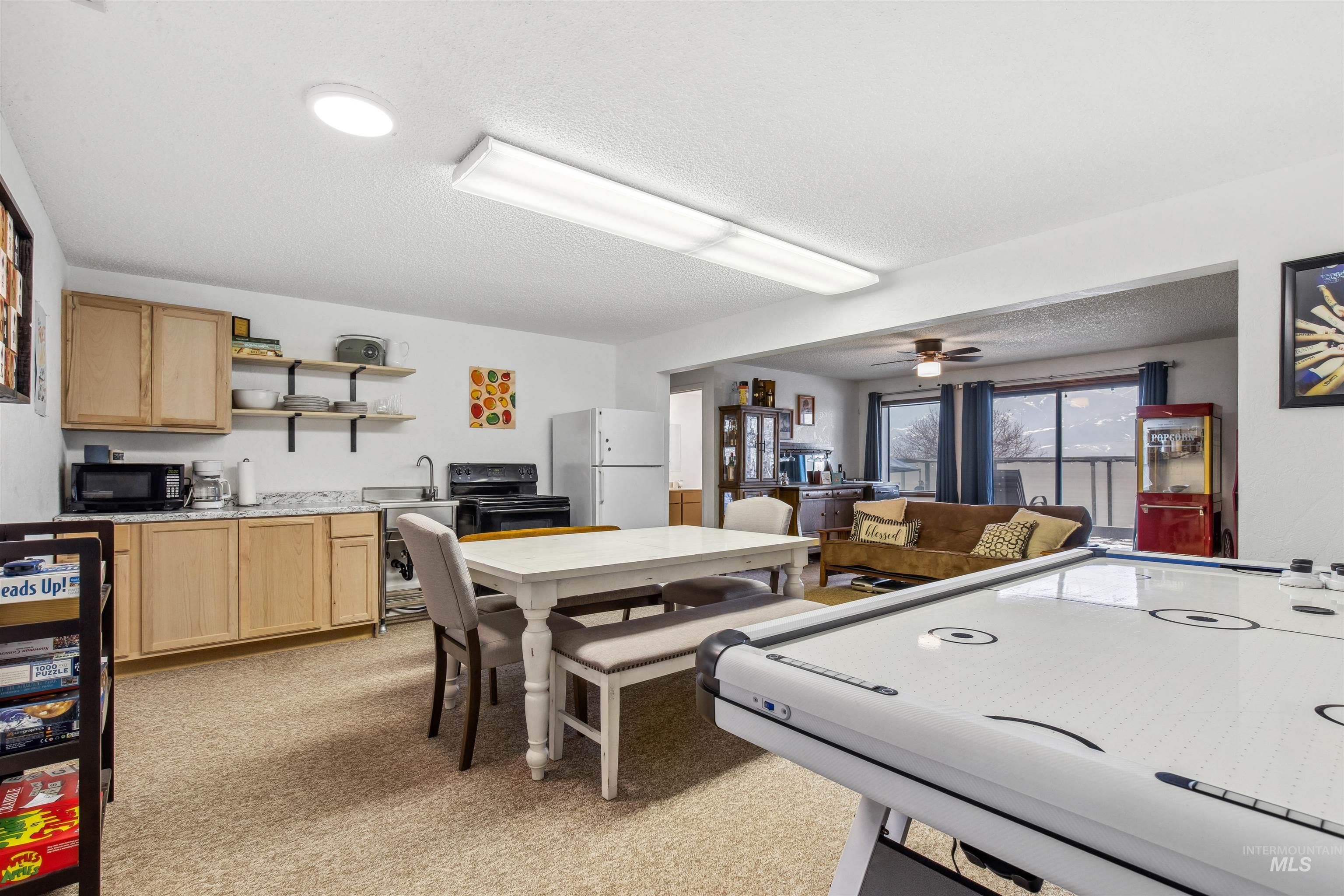 Rec room featuring a textured ceiling, light colored carpet, and a ceiling fan