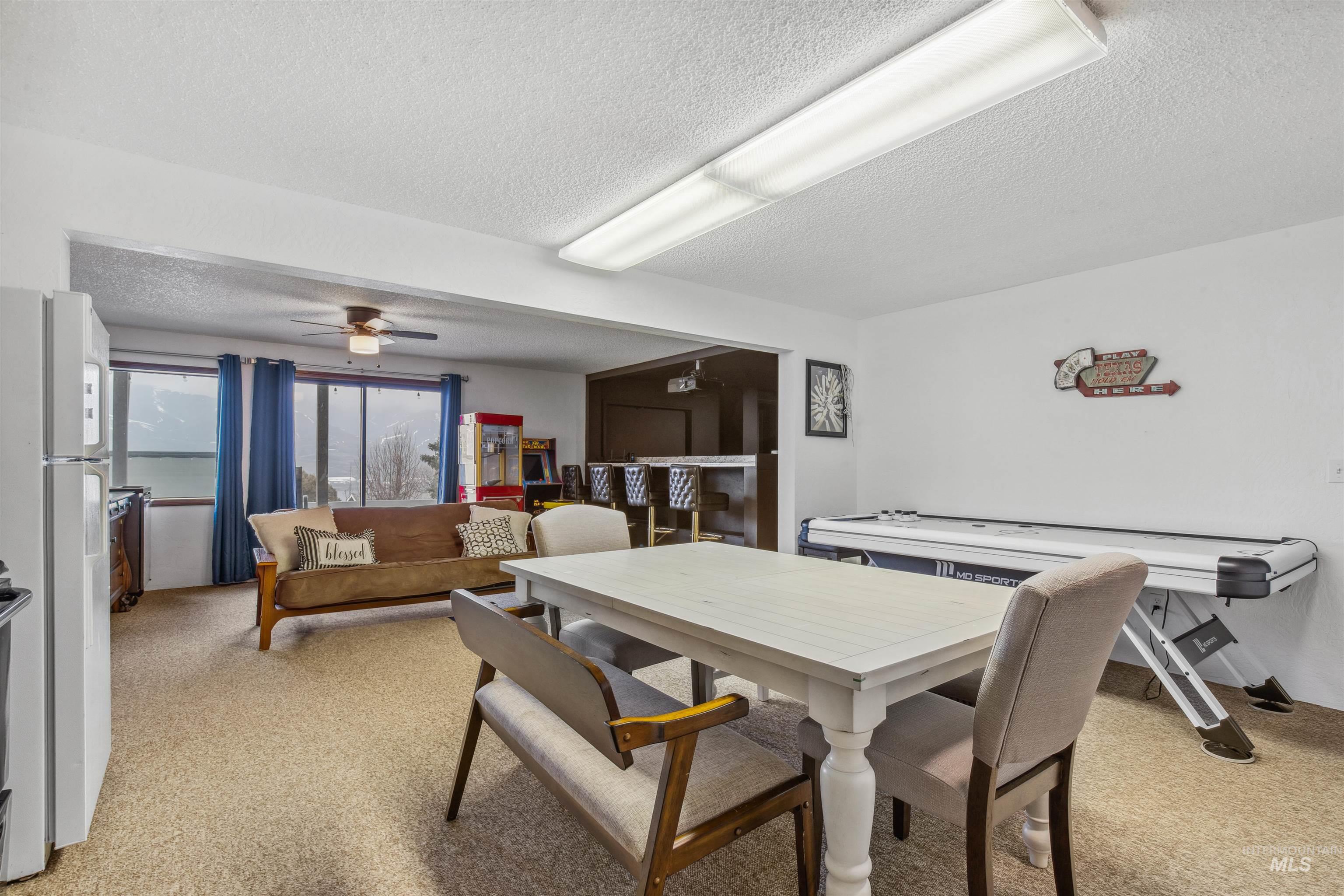 Dining area with light colored carpet, a textured ceiling, and ceiling fan