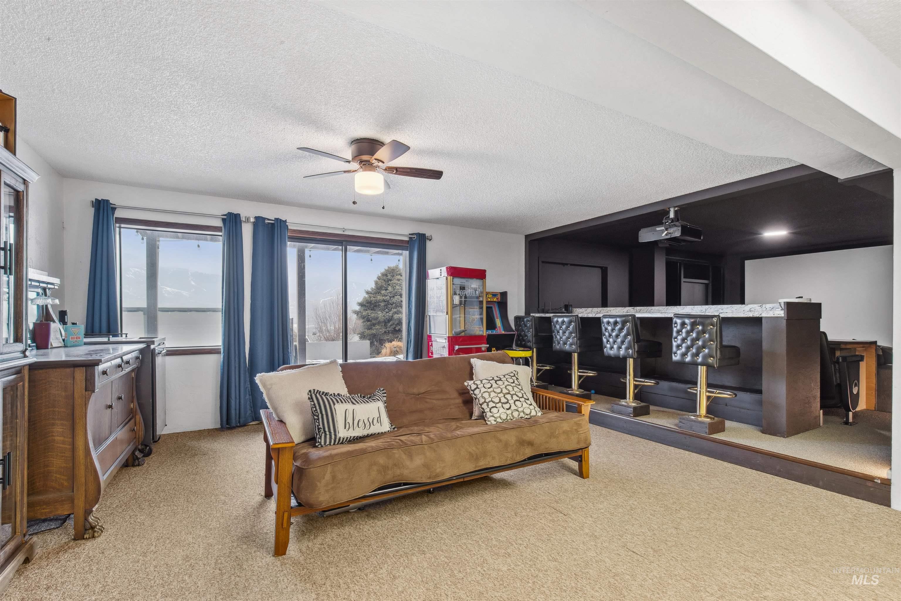 Carpeted living area featuring a textured ceiling, a bar, and ceiling fan