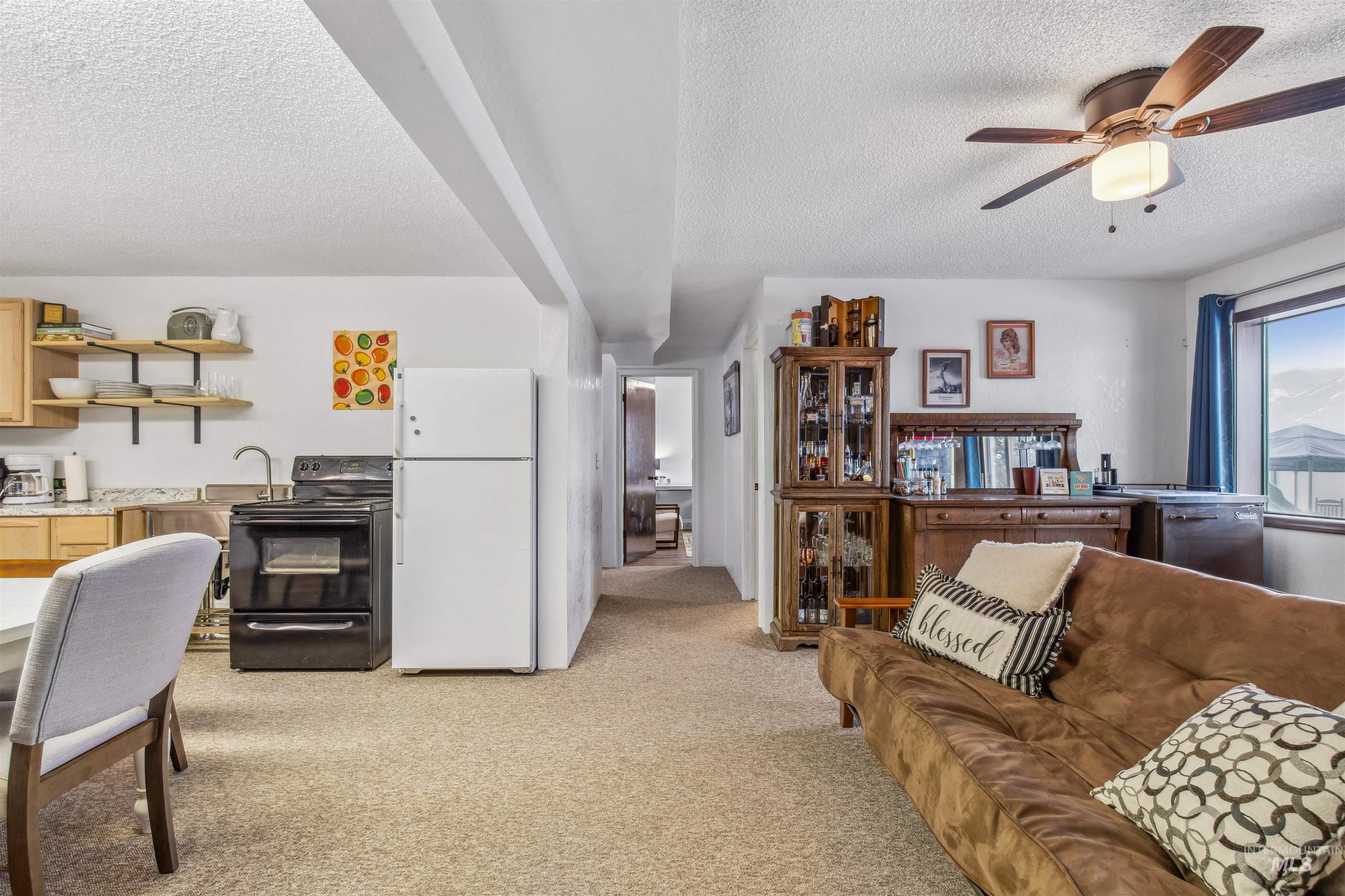 Living room with light carpet, a textured ceiling, and a ceiling fan