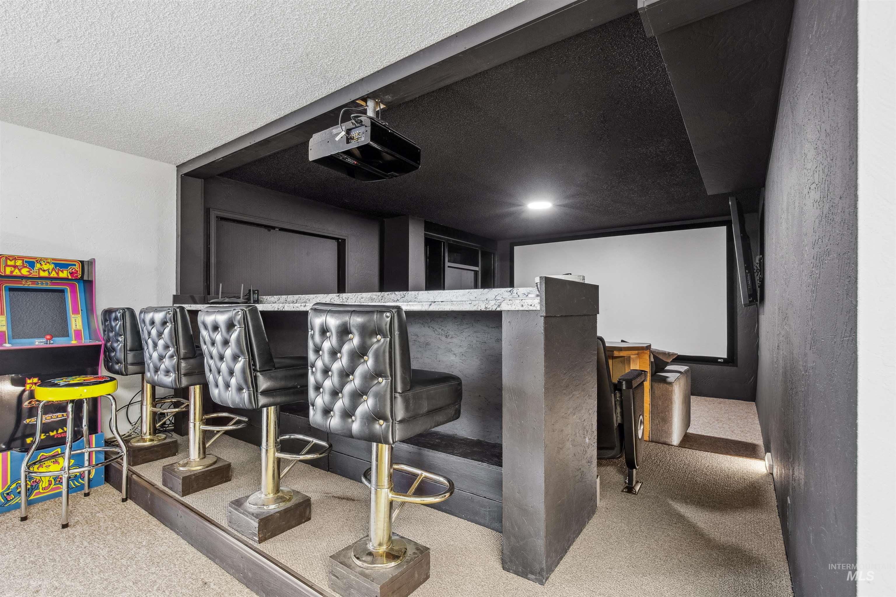 Carpeted cinema room with a textured ceiling and a bar