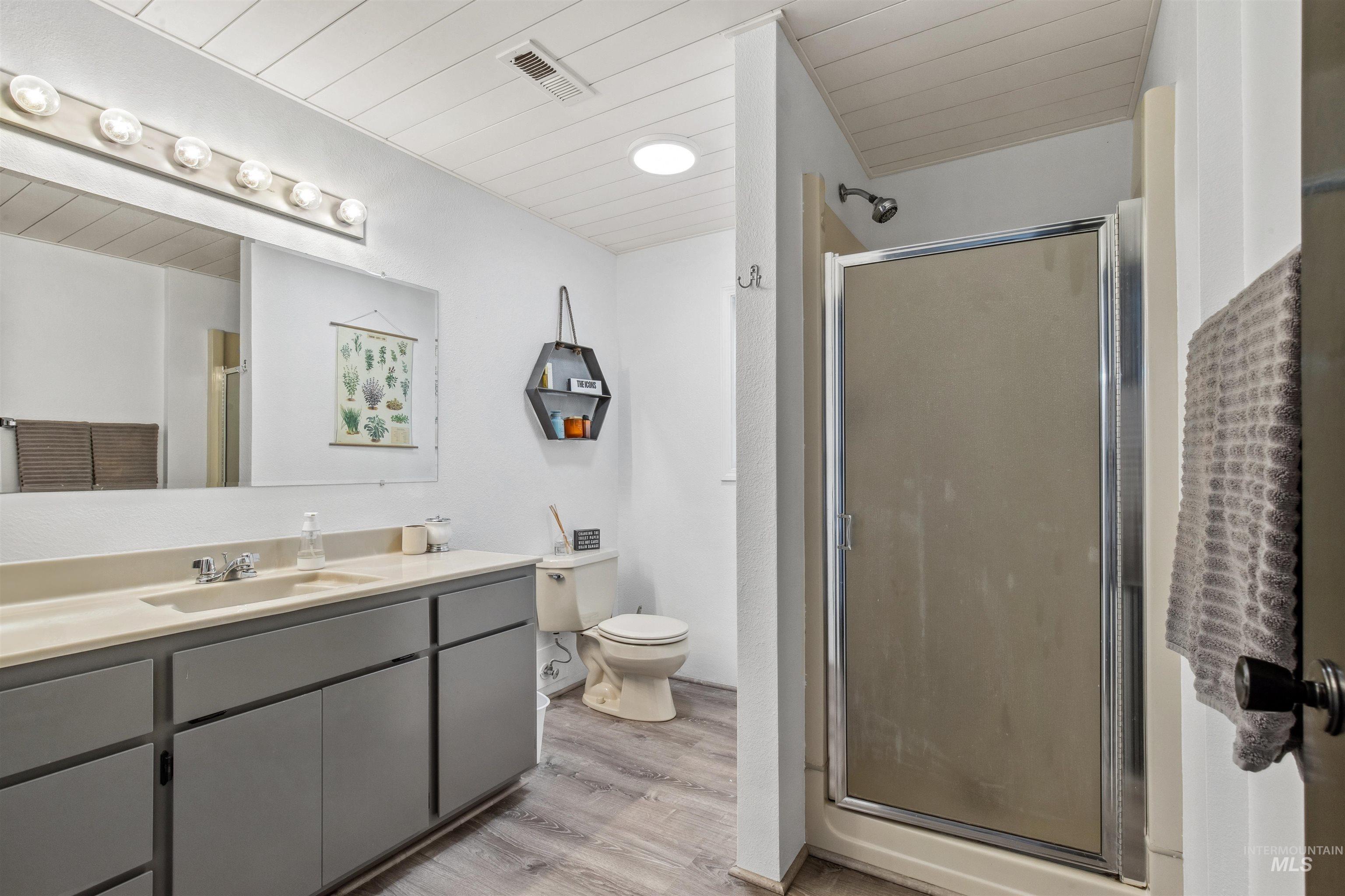 Full bathroom featuring a stall shower, light wood-style floors, wooden ceiling, and vanity