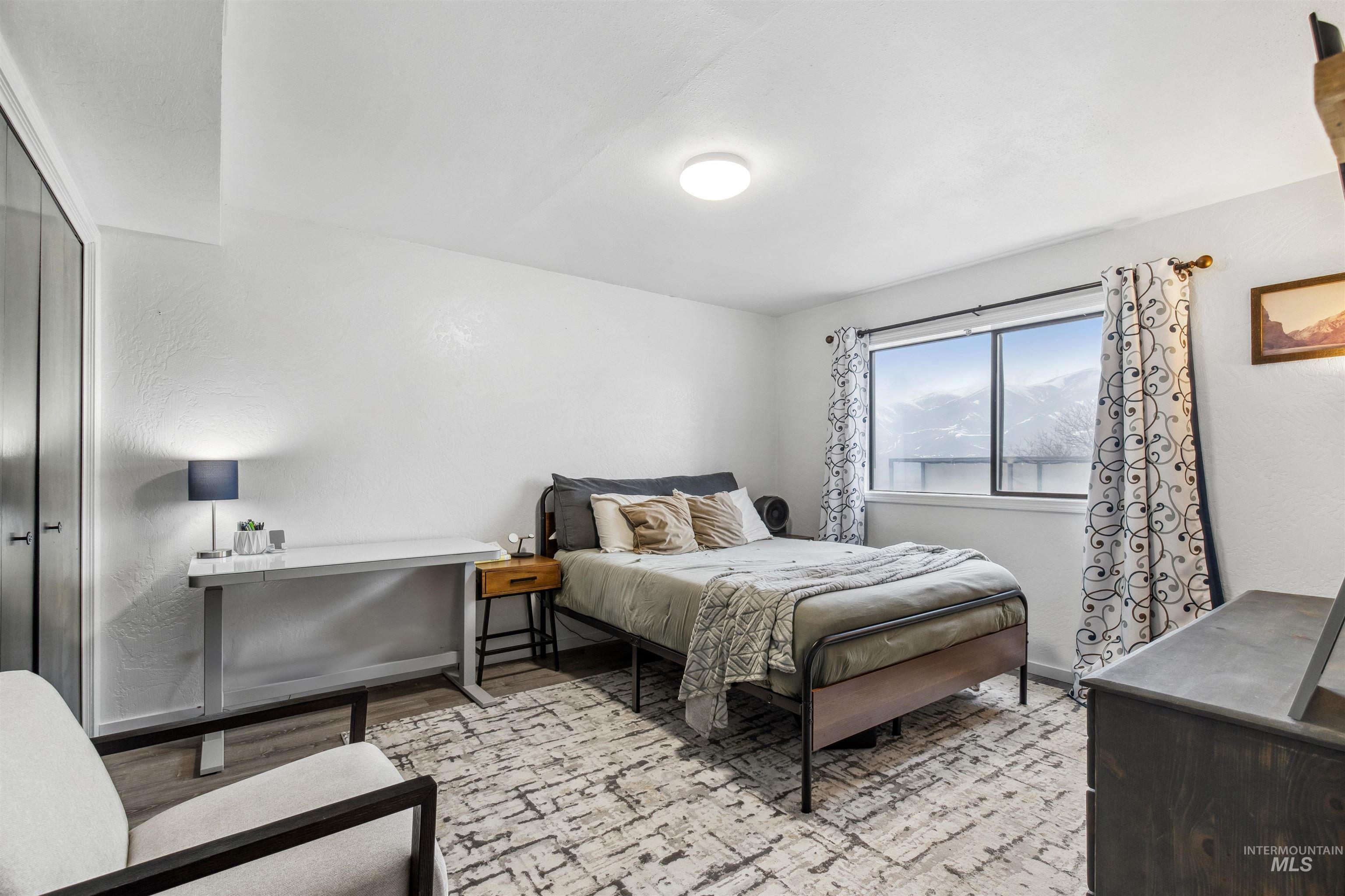 Bedroom with light wood-type flooring and a textured wall