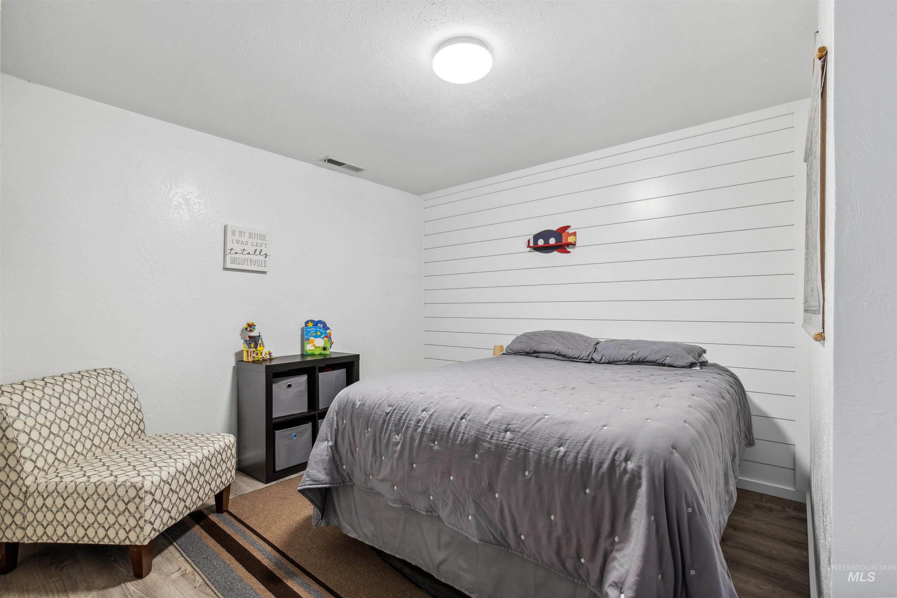 Bedroom featuring wood finished floors and wooden walls