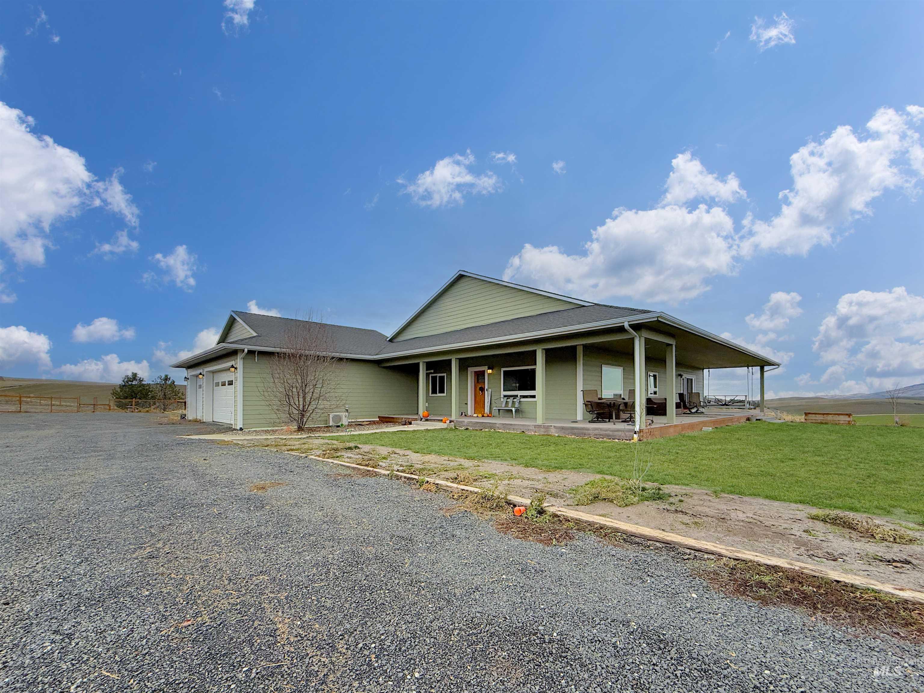 View of front of property featuring an attached garage, covered porch, and gravel driveway