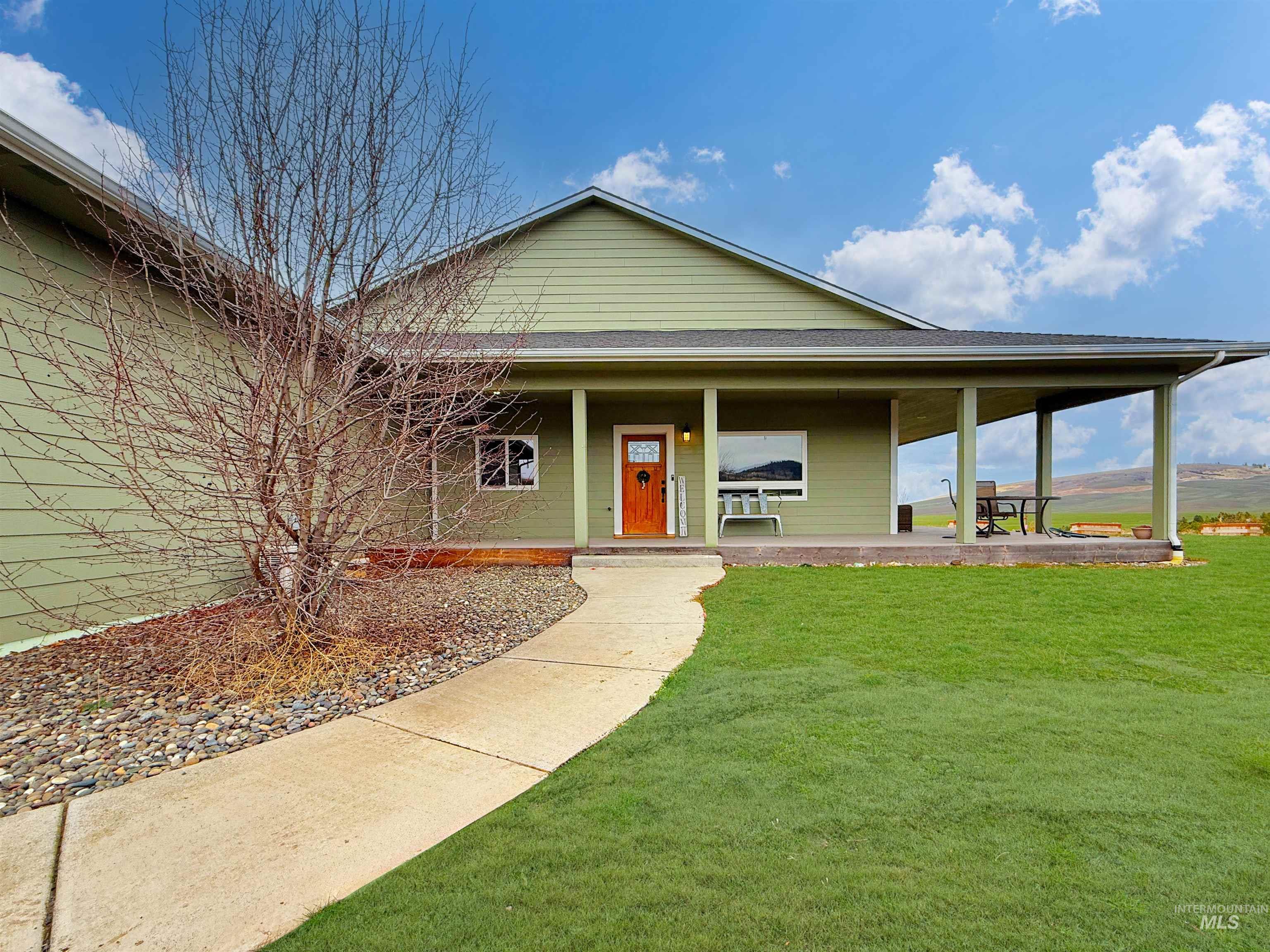 View of front of house featuring covered porch, a front lawn, and roof with shingles