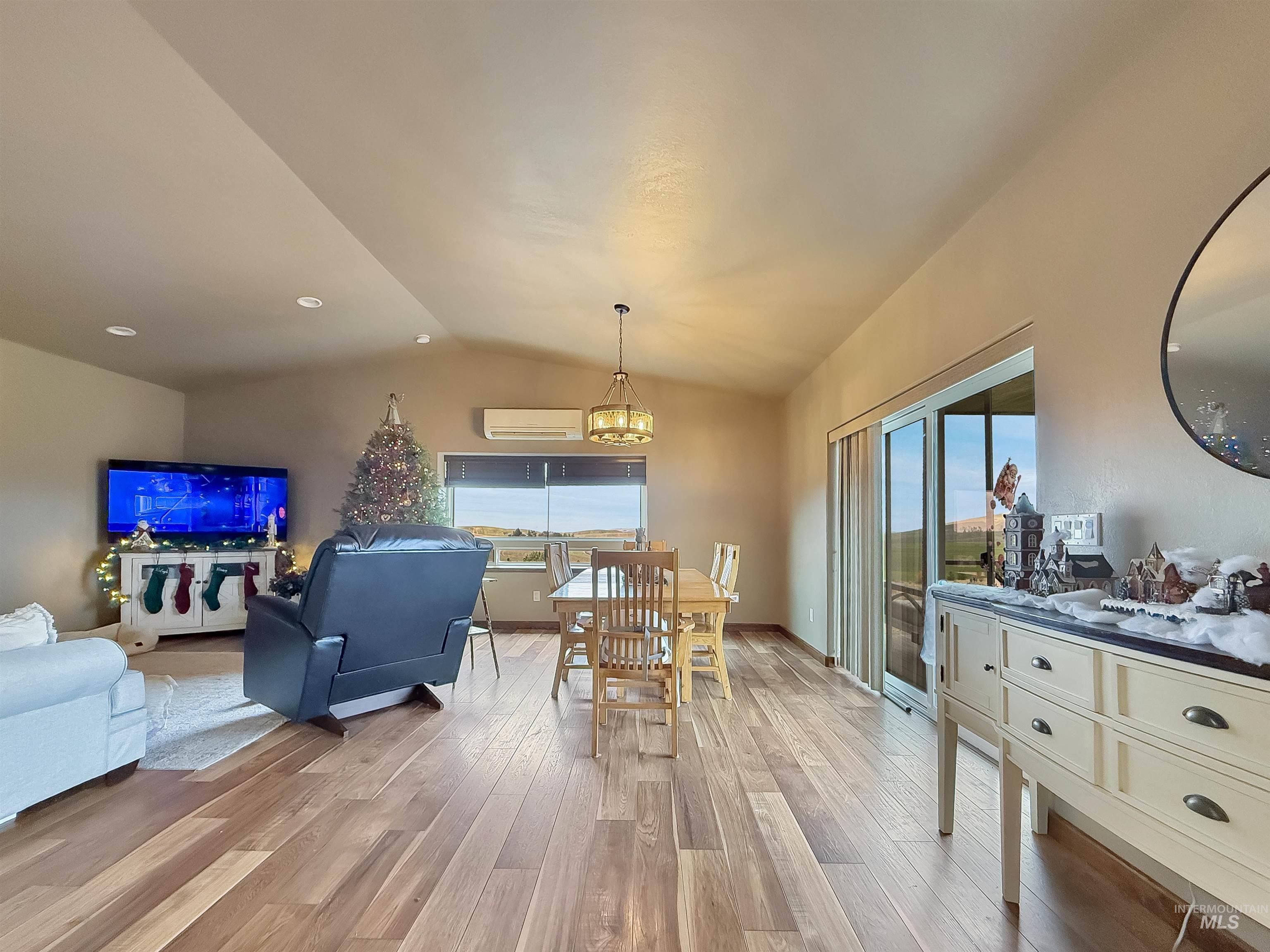 Dining room with lofted ceiling, light wood finished floors, a chandelier, recessed lighting, and a wall mounted air conditioner
