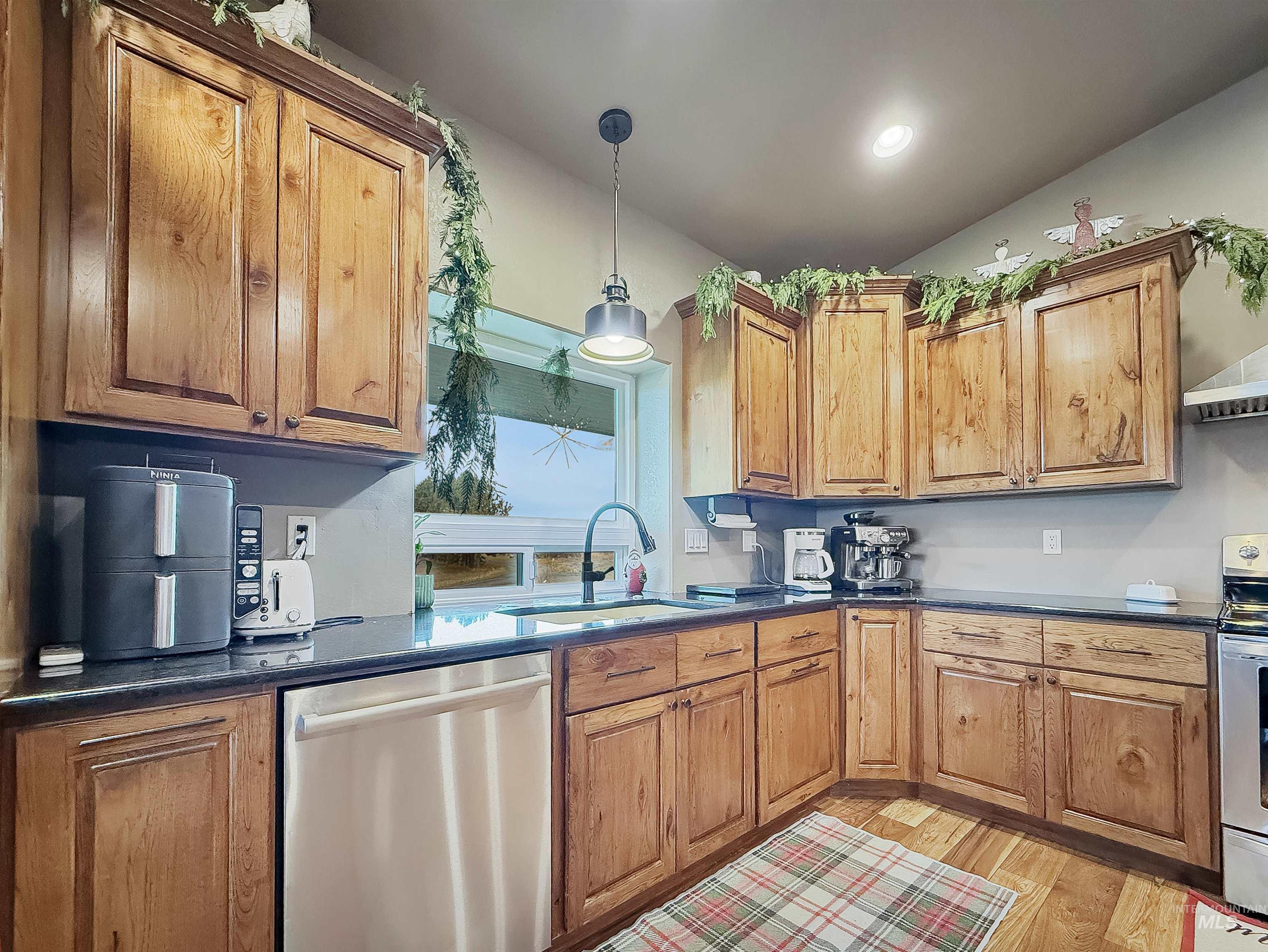 Kitchen featuring decorative light fixtures, appliances with stainless steel finishes, and brown cabinetry