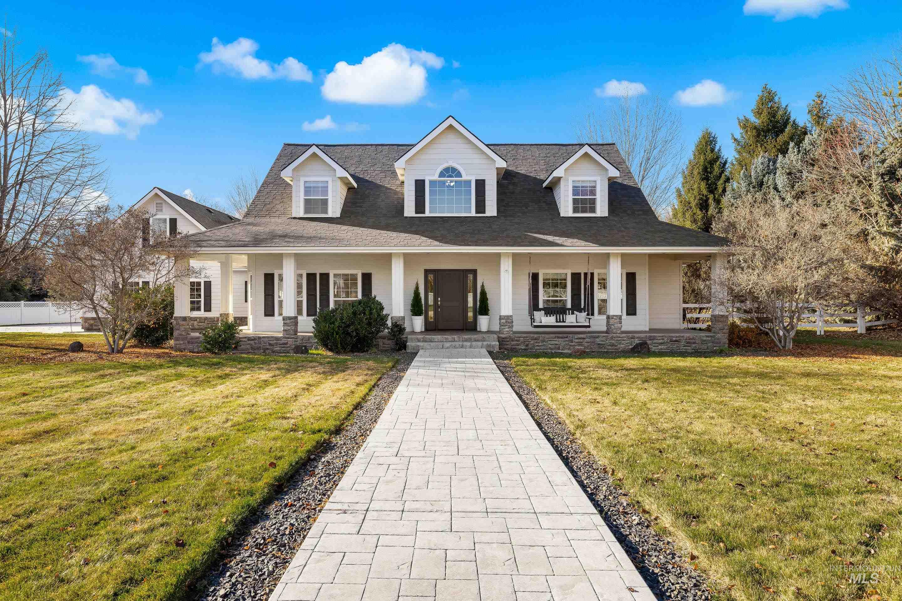 Cape cod-style house with covered porch, a front lawn, stone siding, and a shingled roof