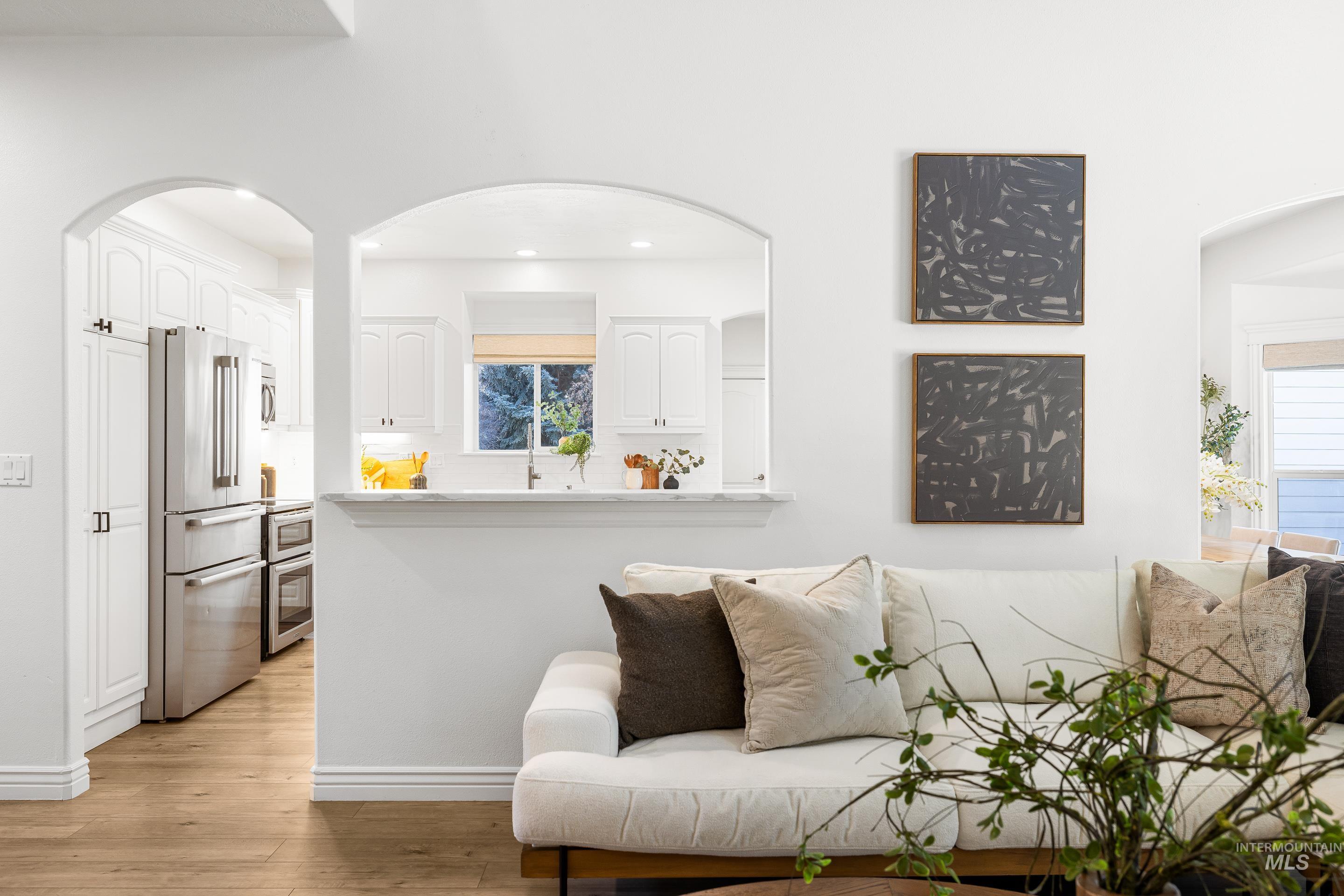 Living room with arched walkways and light wood-style flooring