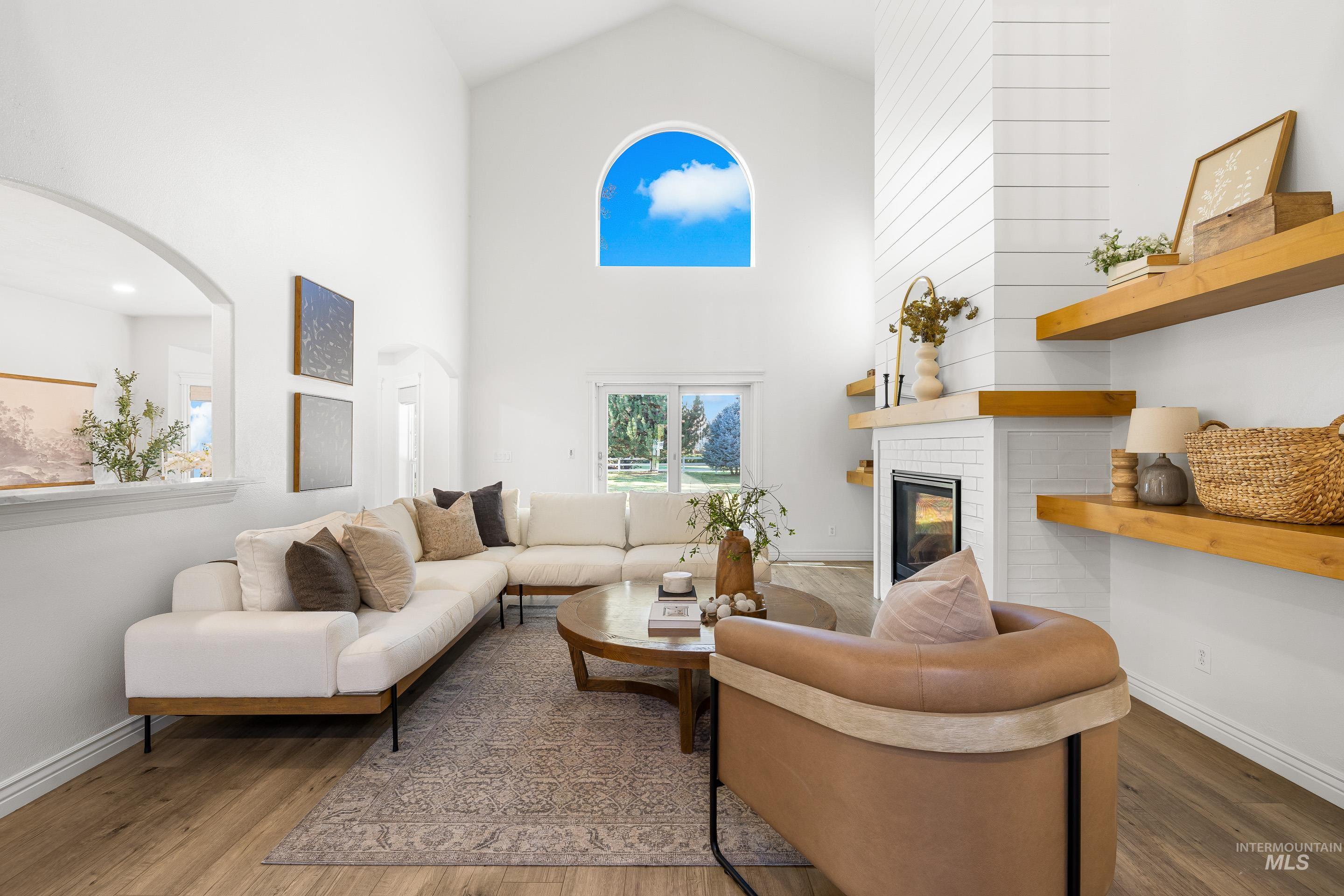 Living area with high vaulted ceiling, a fireplace, and wood finished floors