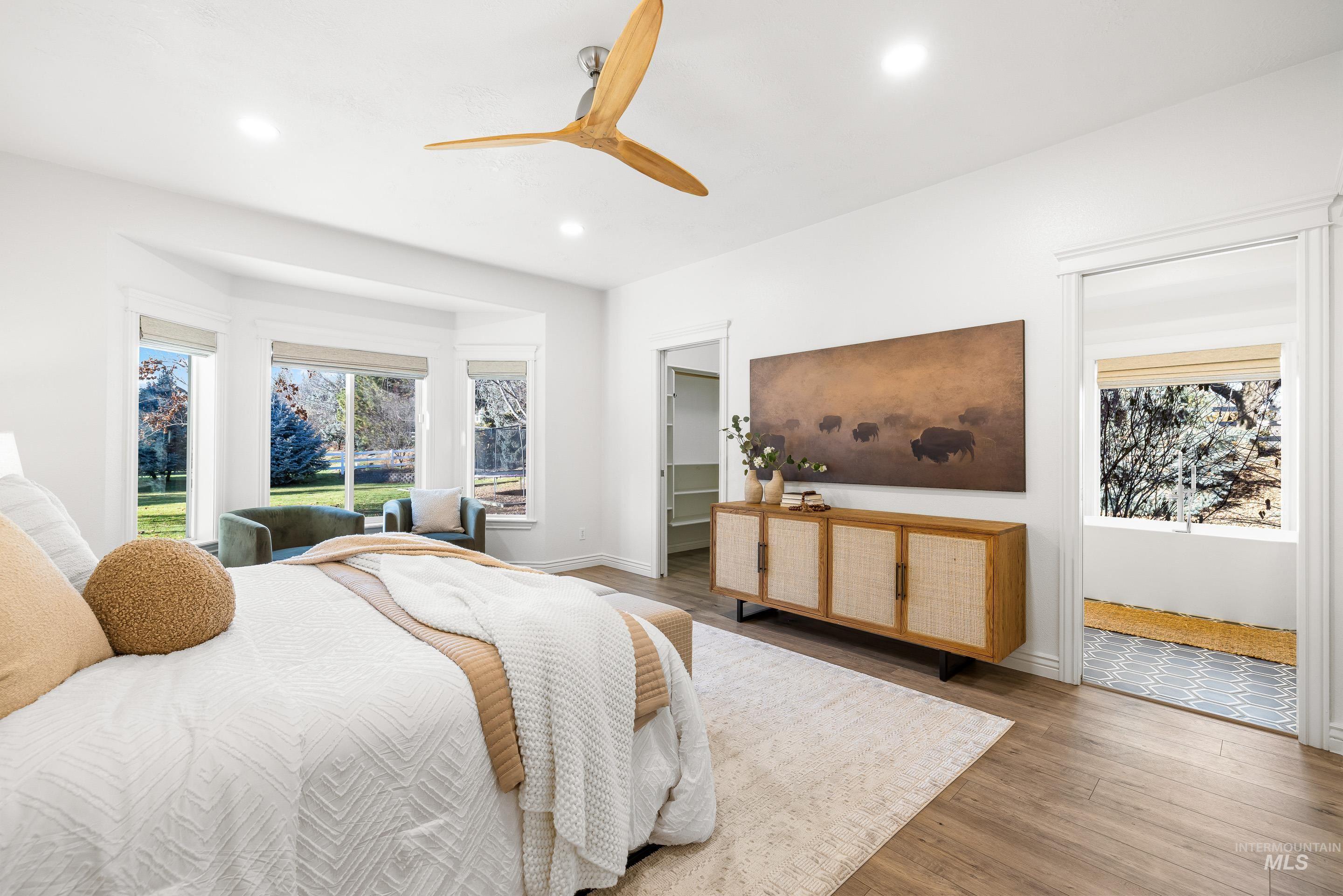 Bedroom featuring a walk in closet, wood finished floors, a ceiling fan, and recessed lighting