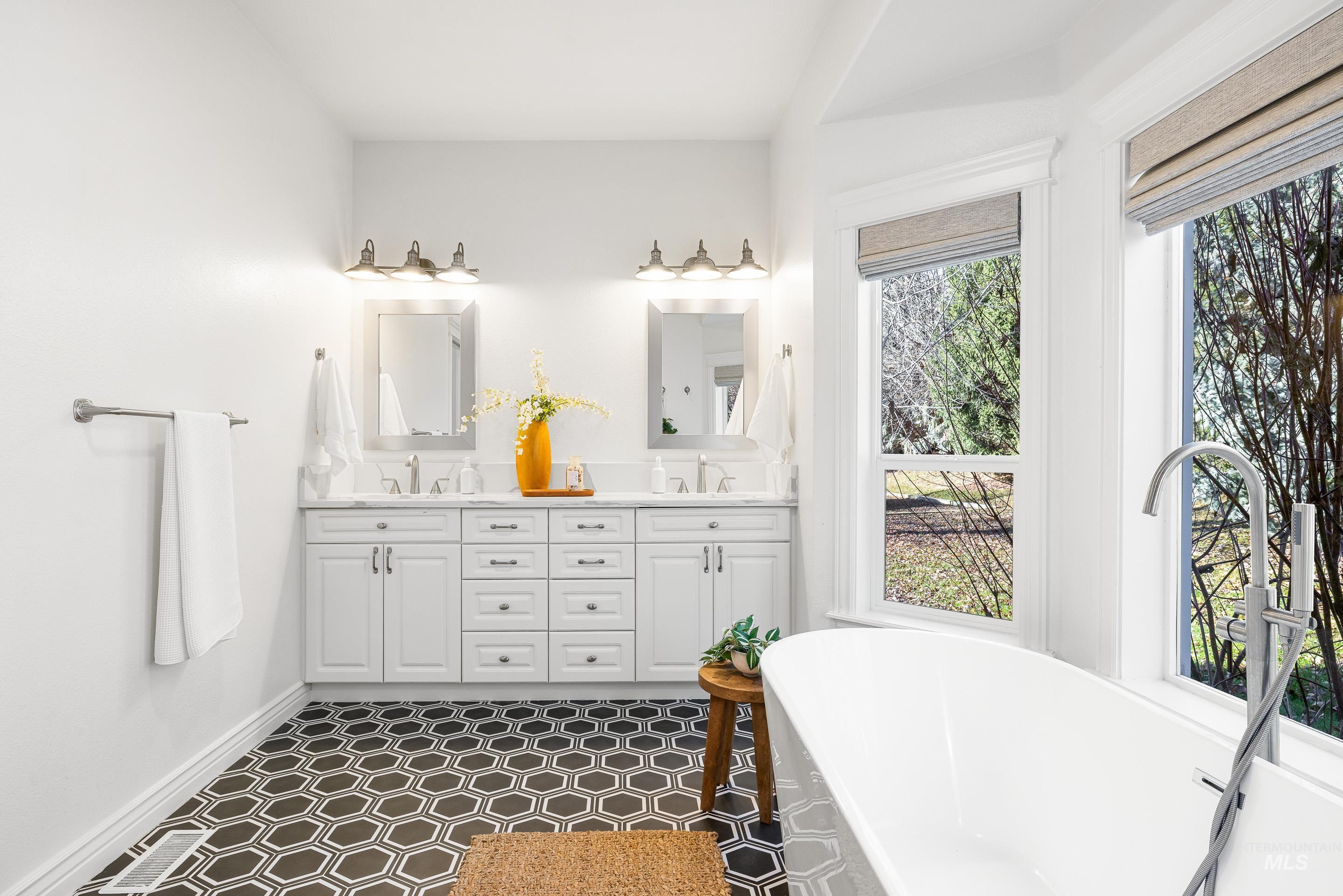 Full bathroom featuring a freestanding tub, double vanity, and dark floors