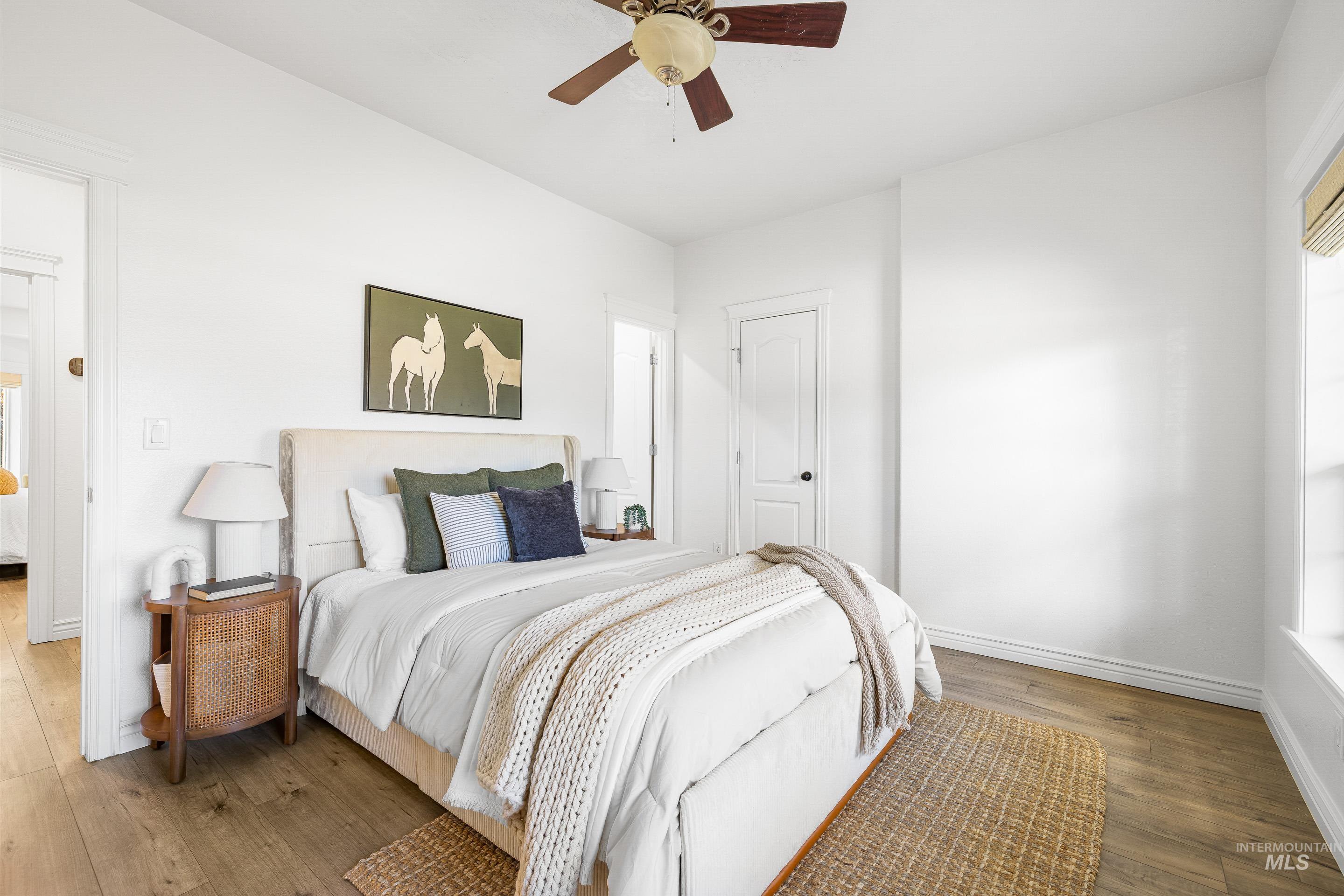 Bedroom with wood-type flooring, ceiling fan, and multiple windows