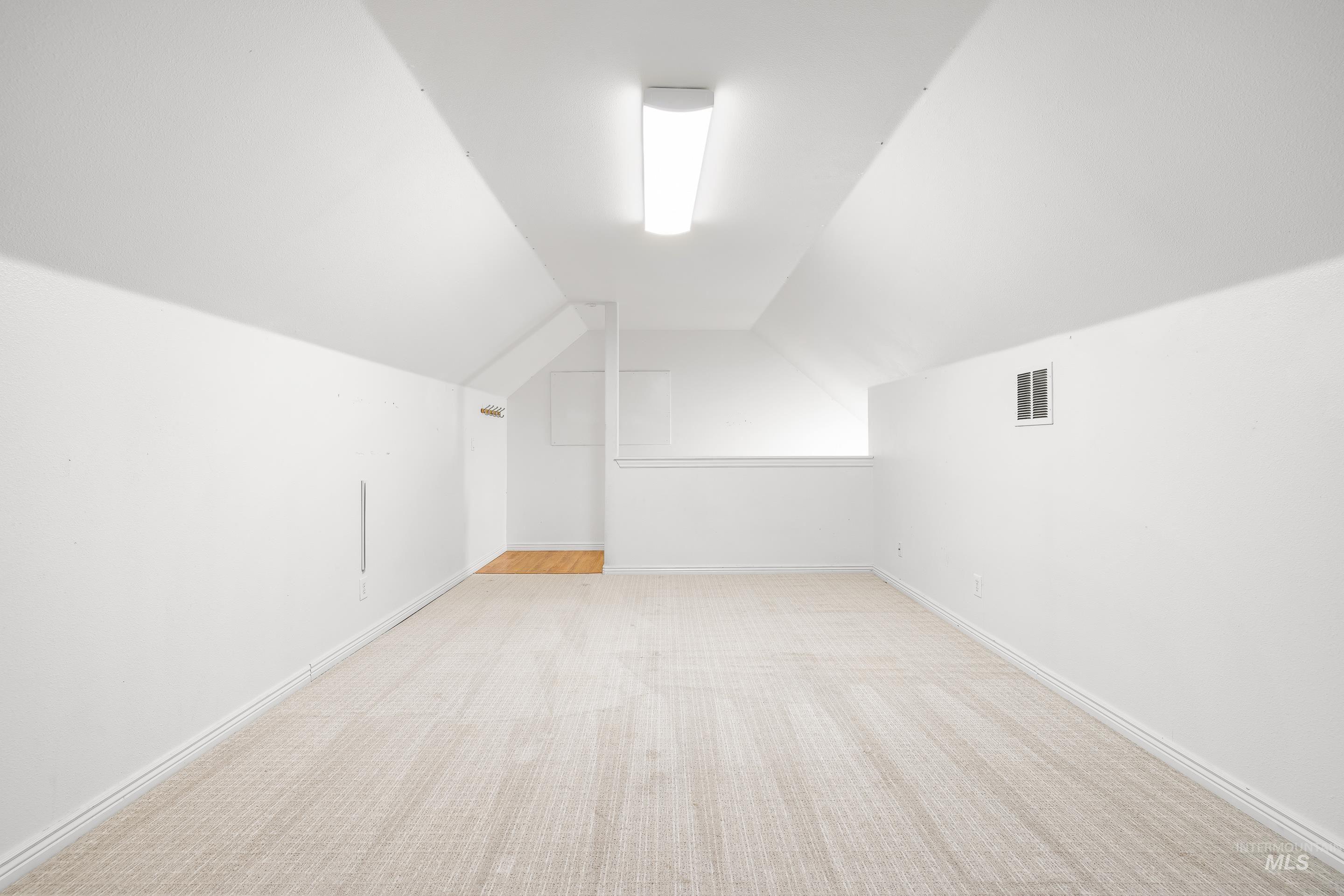 Additional living space with lofted ceiling and light colored carpet
