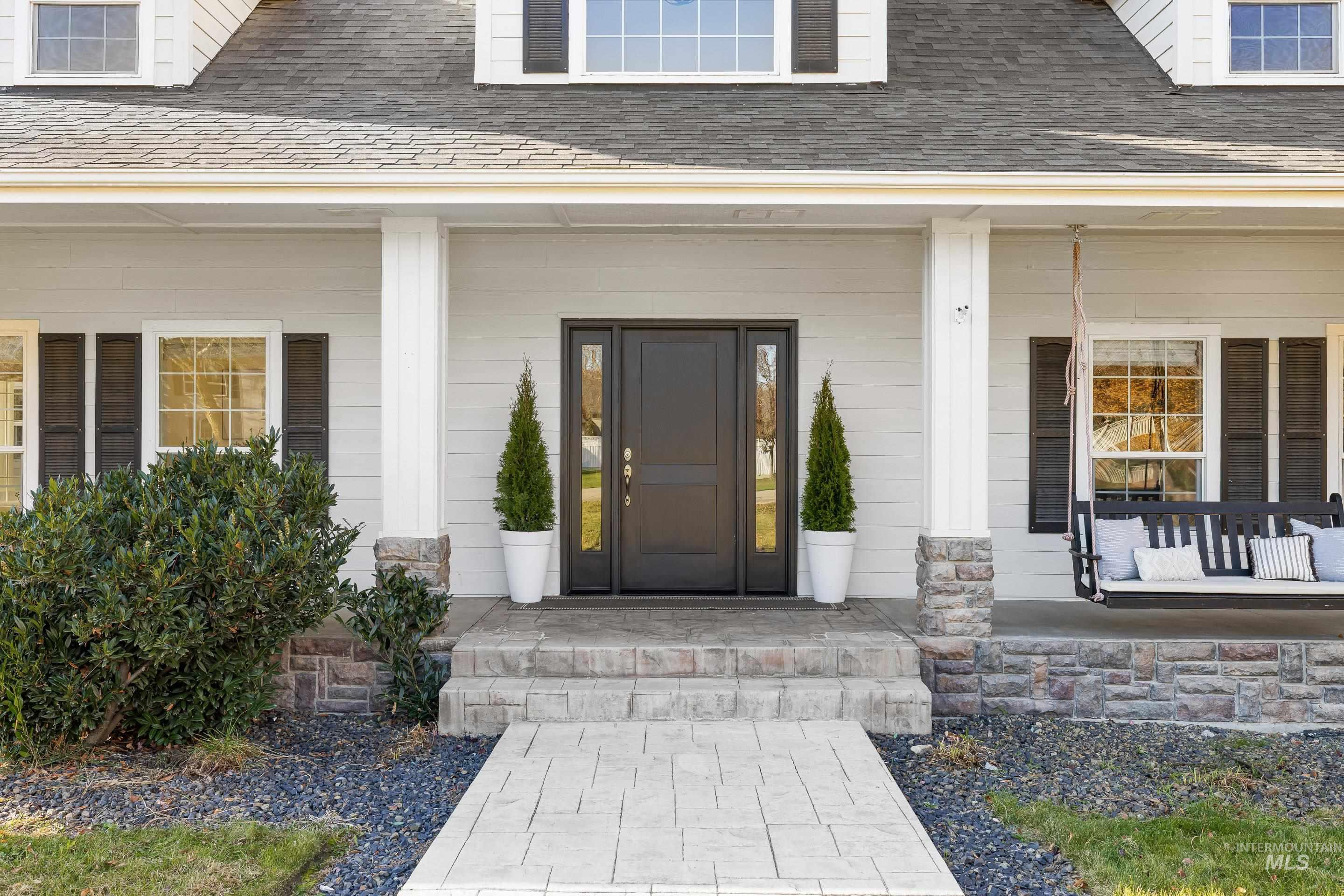 Doorway to property with covered porch and a shingled roof