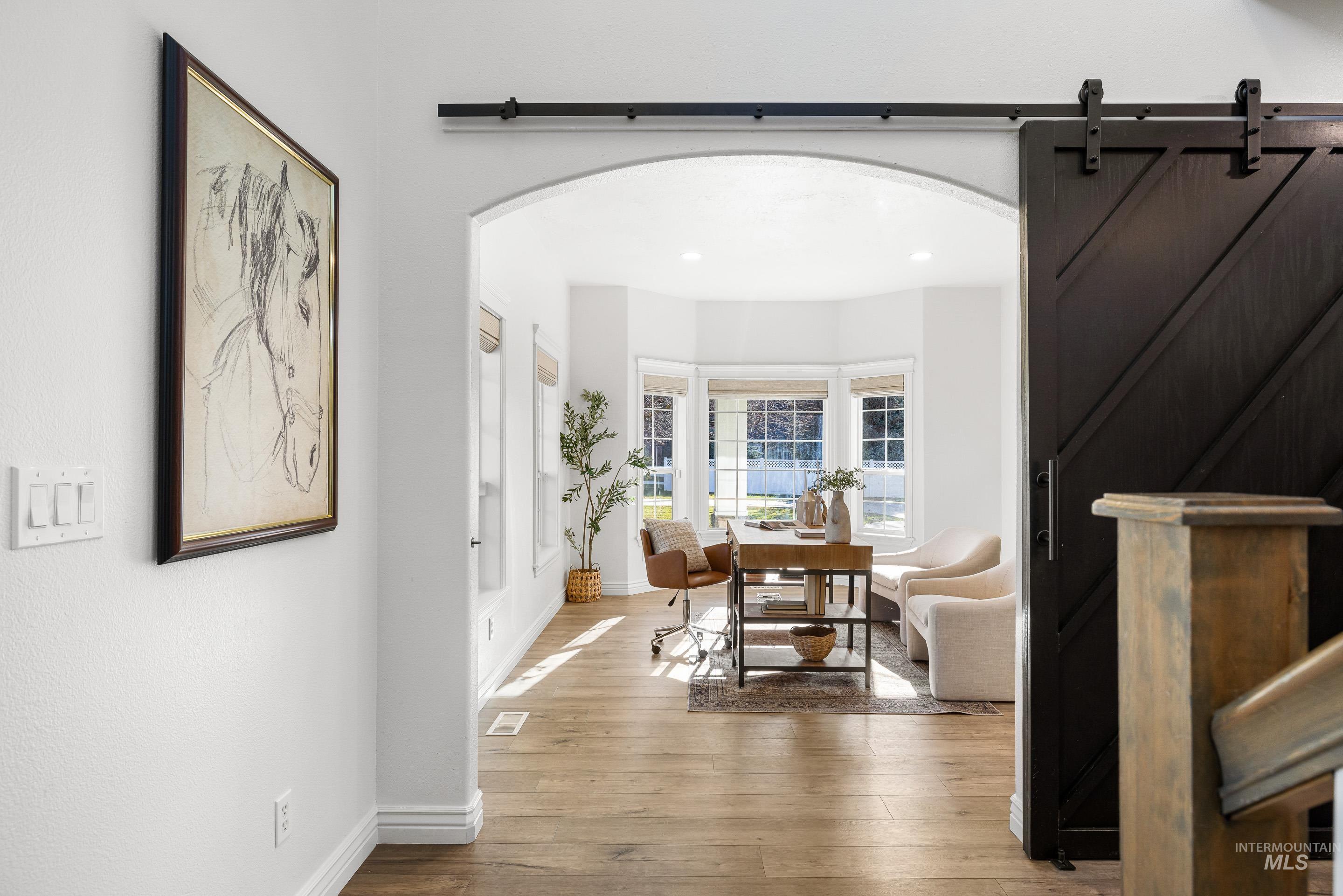 Hall featuring arched walkways, a barn door, and light wood-type flooring