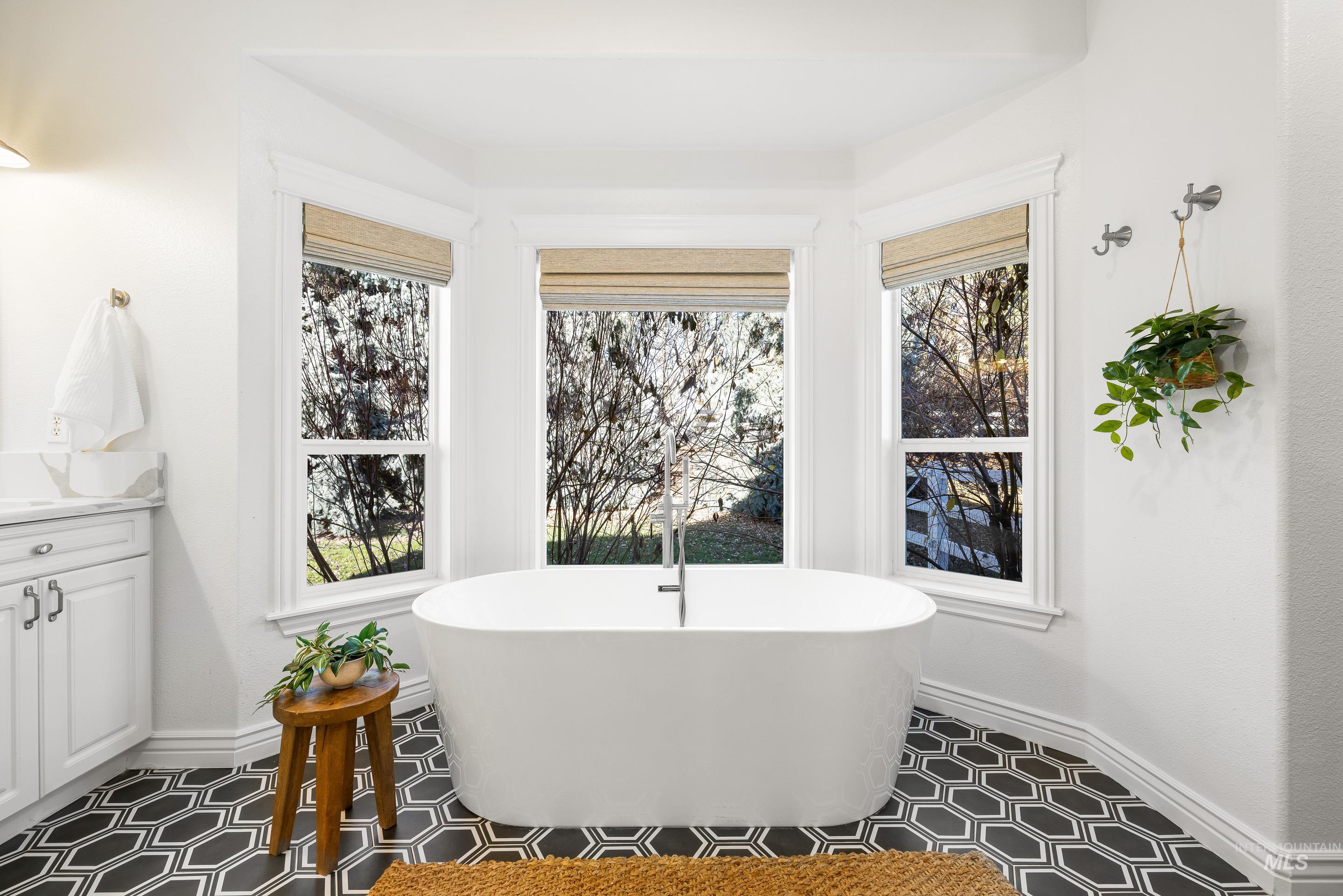 Full bath featuring a freestanding bath, vanity, and plenty of natural light