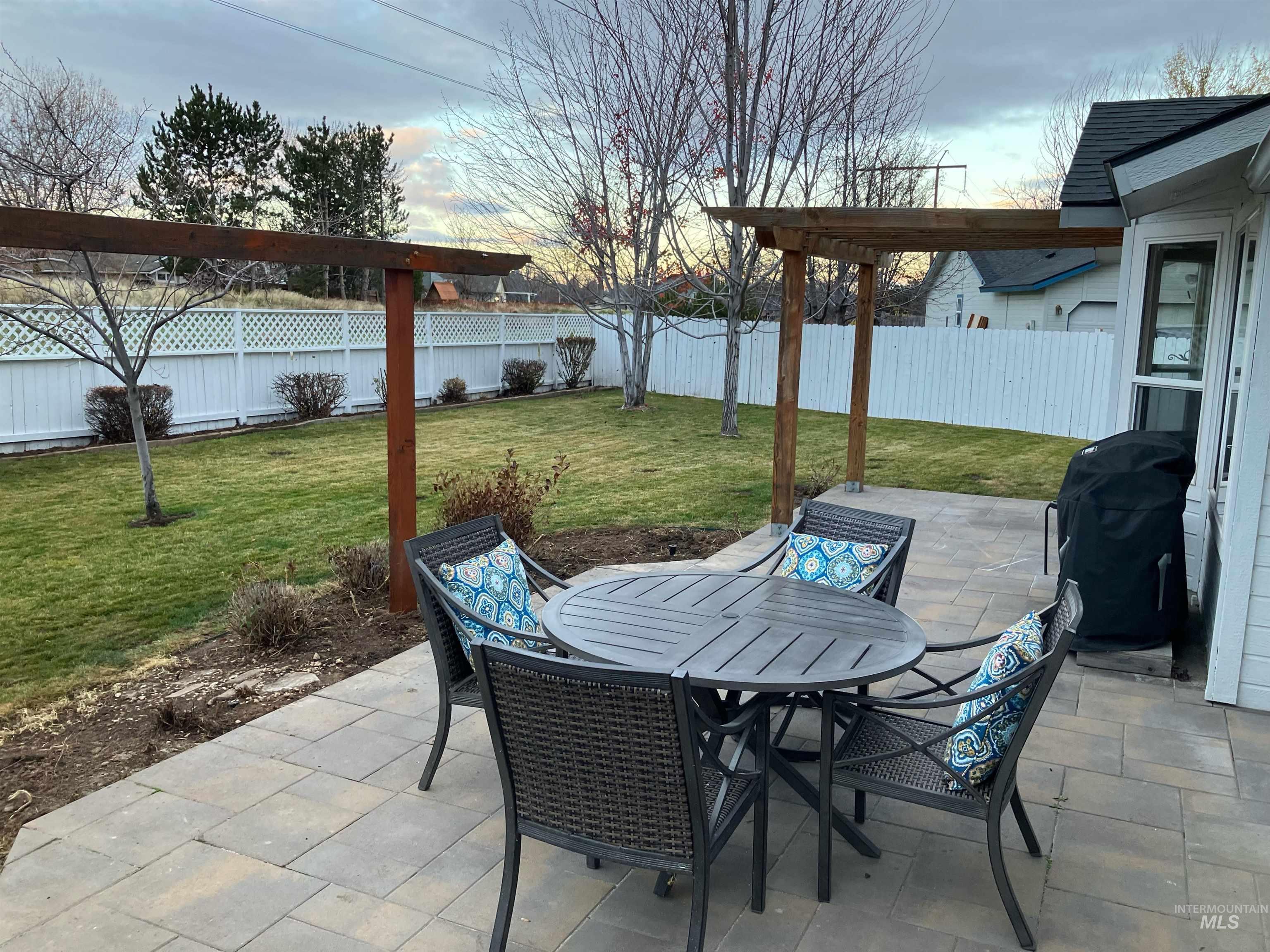 Fenced backyard with a patio area, grilling area, outdoor dining space, and a pergola