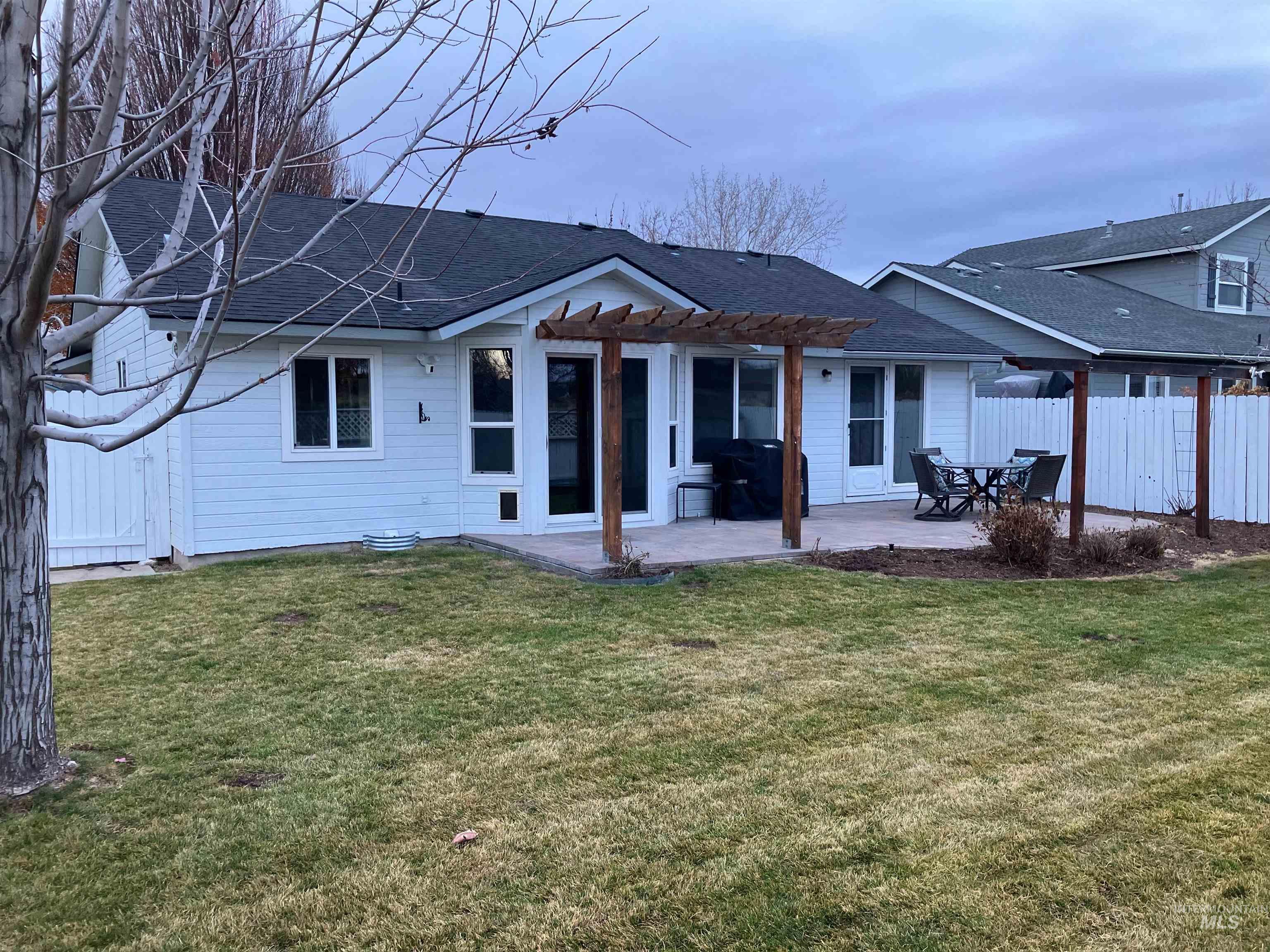 Back of property featuring a patio area, a pergola, and roof with shingles